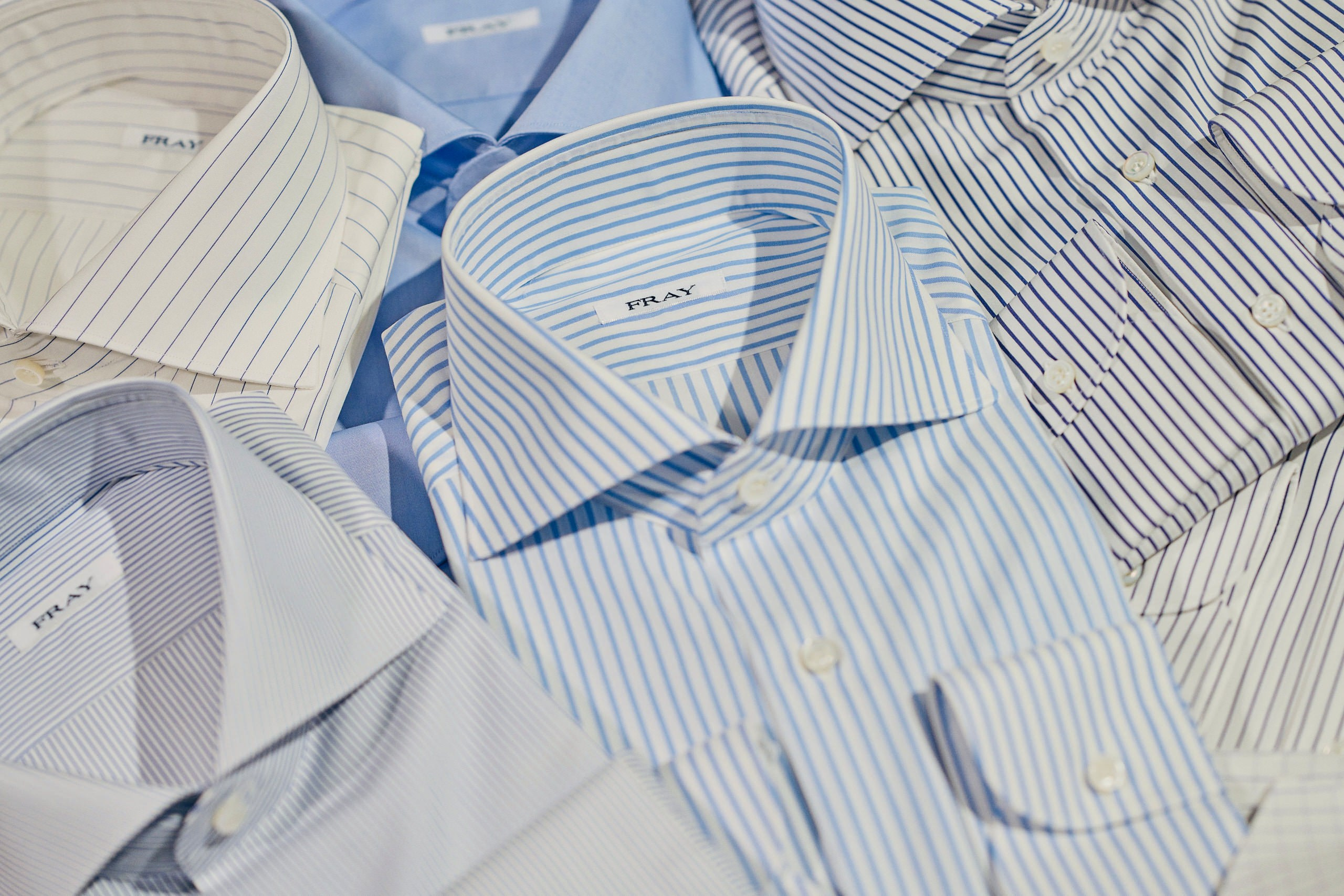 Produktfotografie Wien – Flach gelegte Hemden in unterschiedlichen Blautönen.