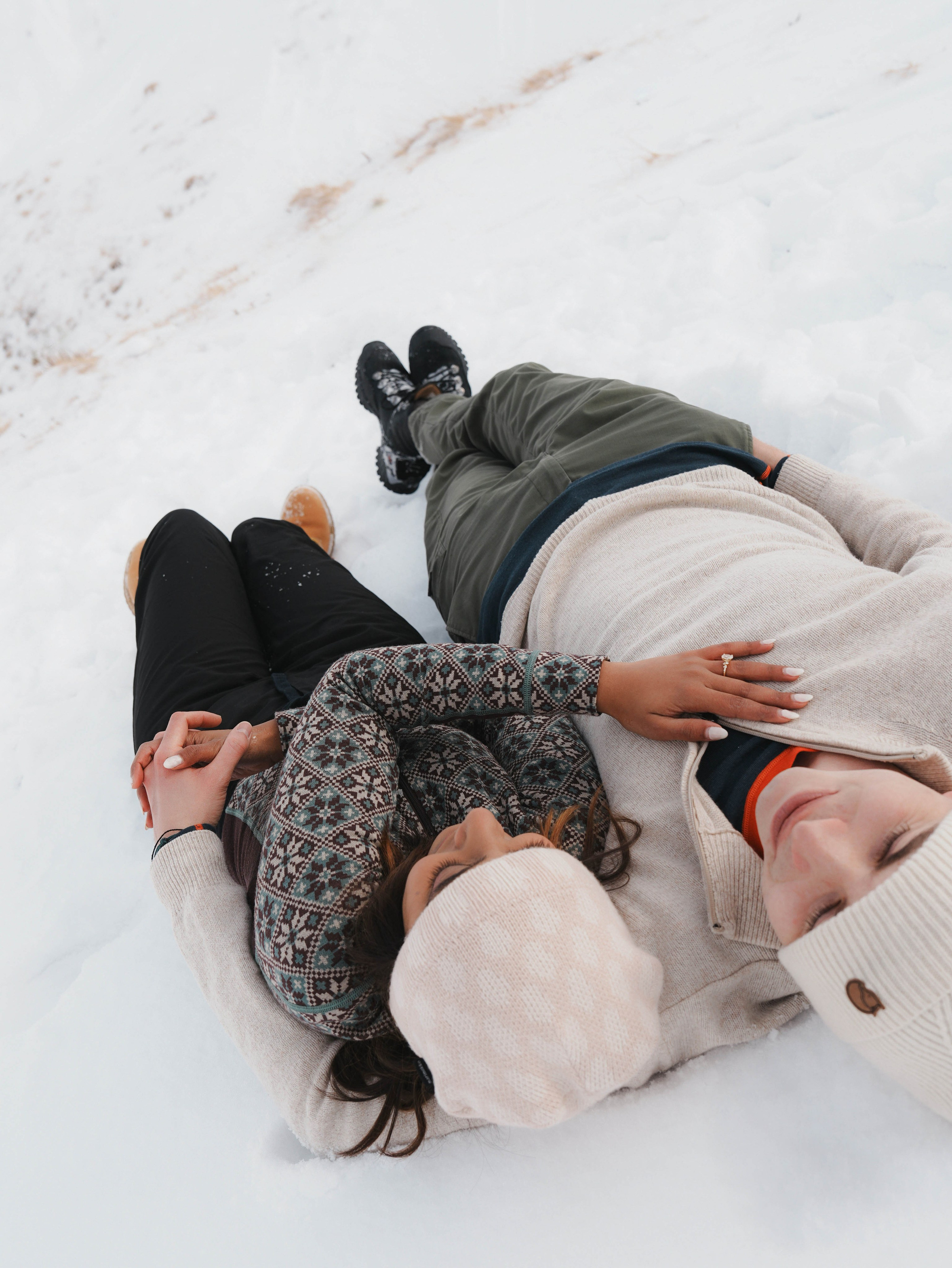Couple lying in snow during winter photoshoot