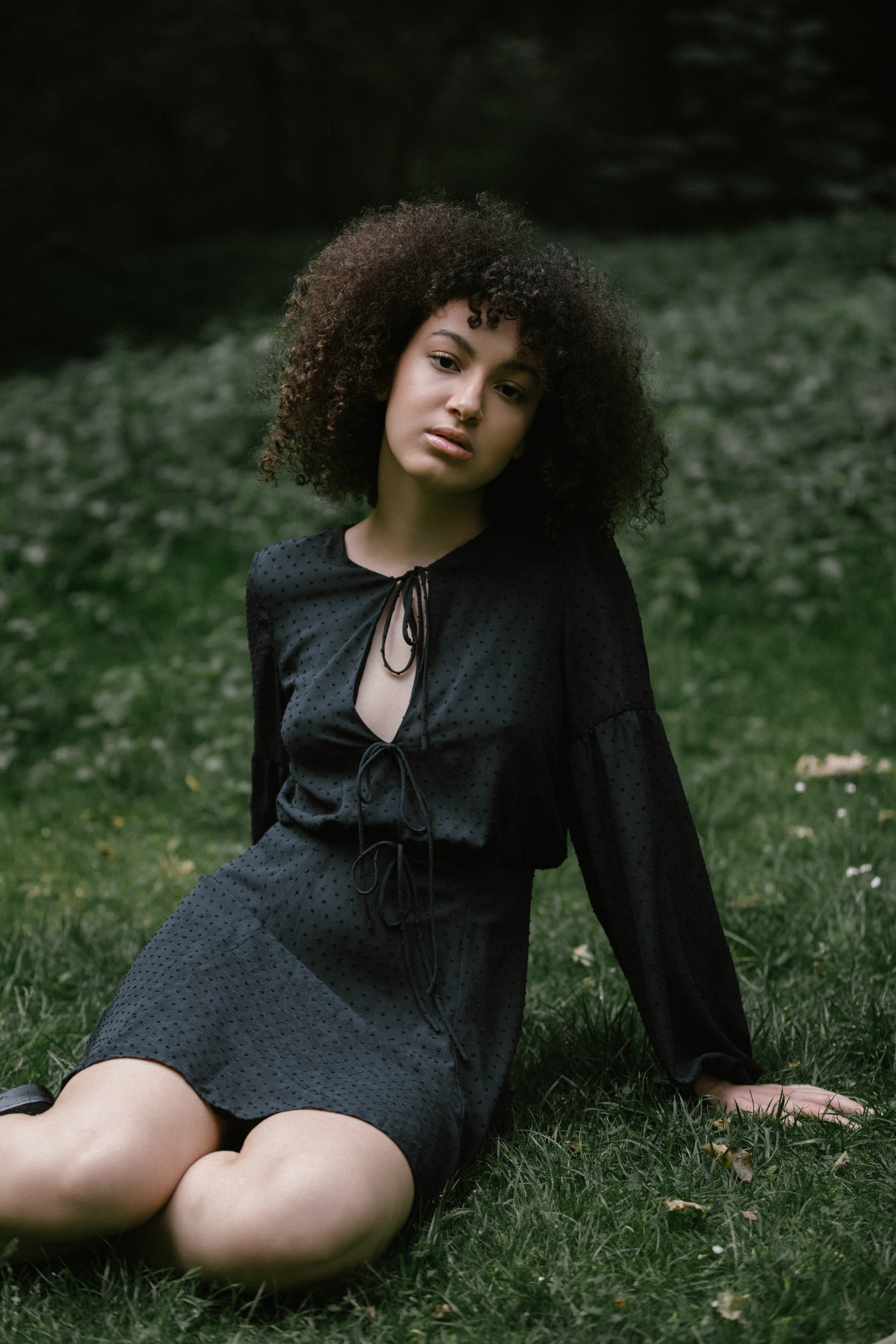 Porträt bei natürlichem Licht, Frau sitzt im Gras, direkter Blick