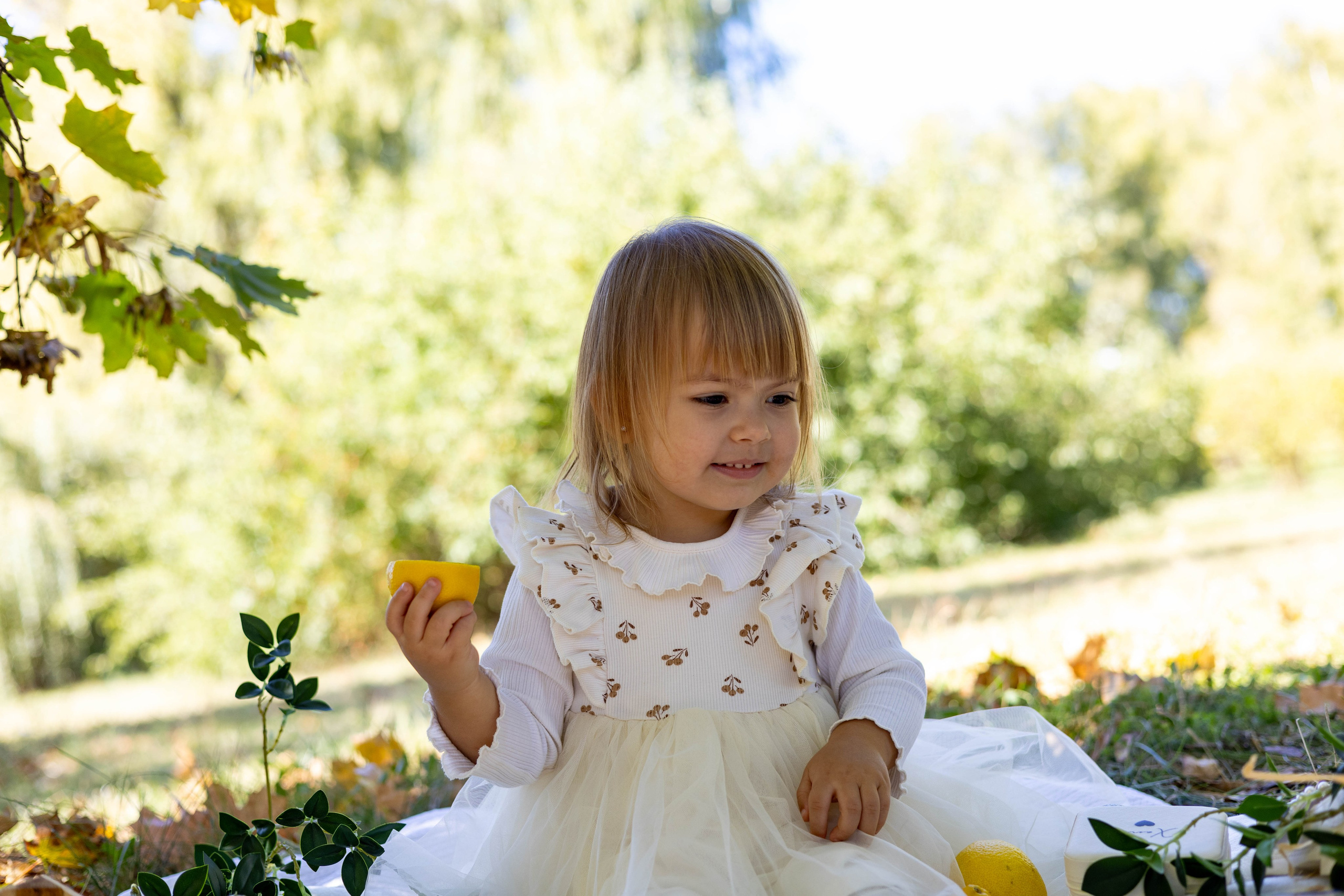 Девочка смеется и держит лимоны в руках на фотосессии