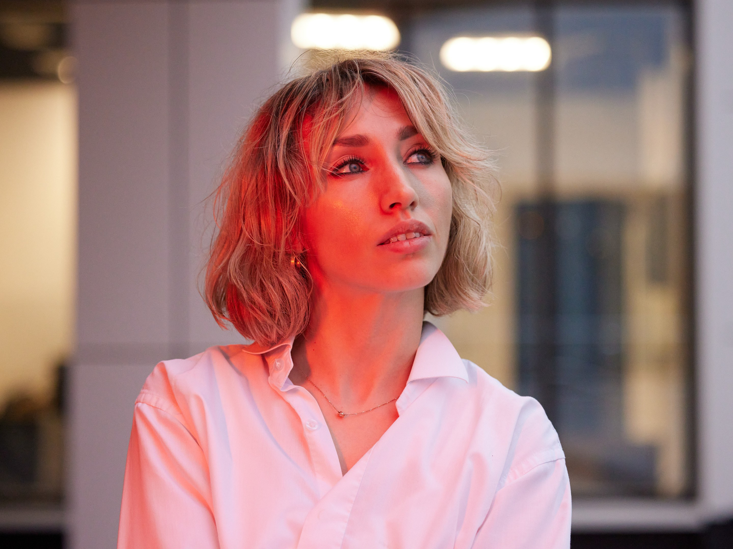 Location portrait of a young woman in red lighting against the backdrop of a building - photographer Andrey Dunin