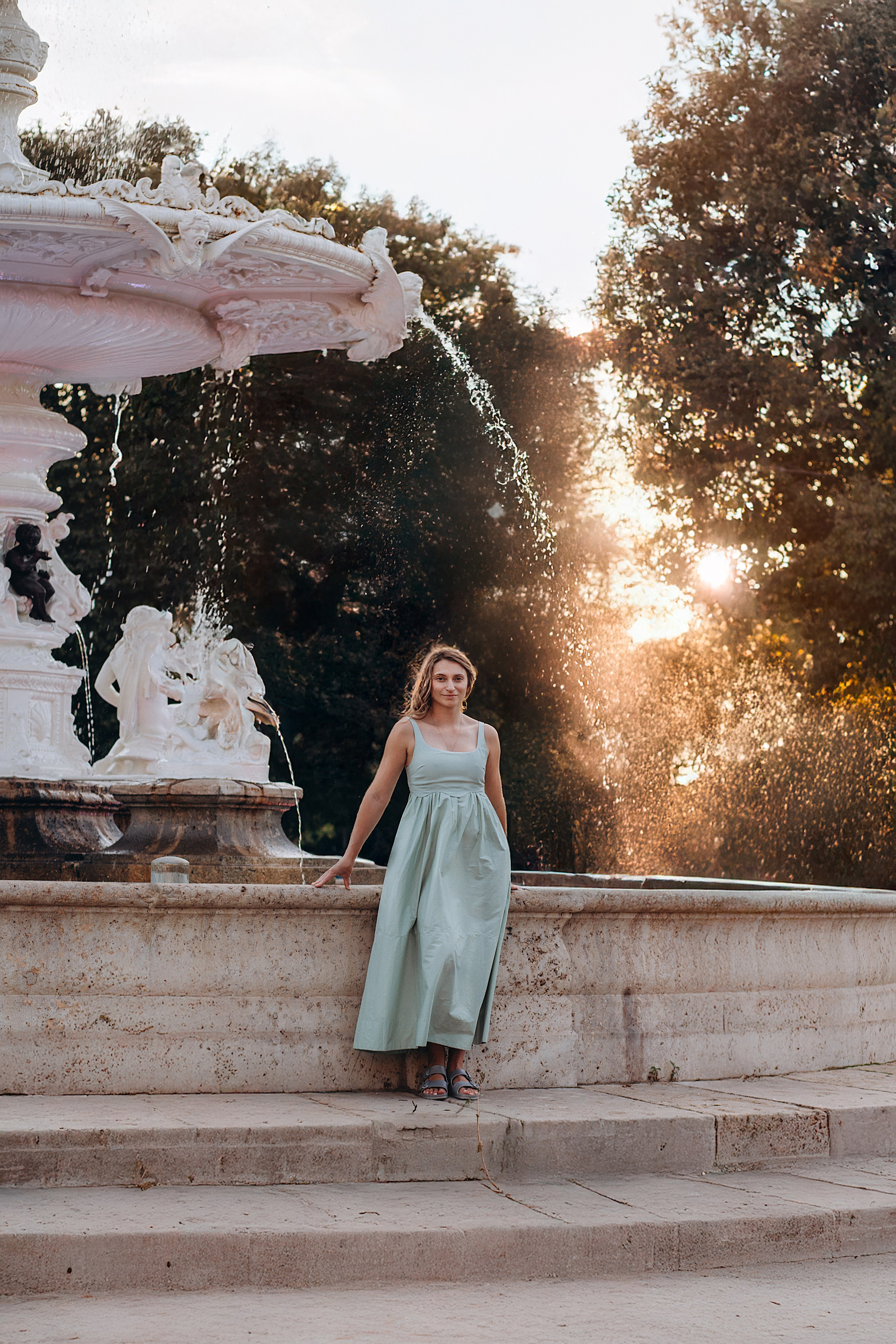 Элегантный женский портрет, снятый в Валенсии, Испания, с женщиной в полосатом платье у классического белого фонтана на закате — идеально для тех, кто ищет романтичные уличные женские фотосессии в Валенсии и по всей Испании.