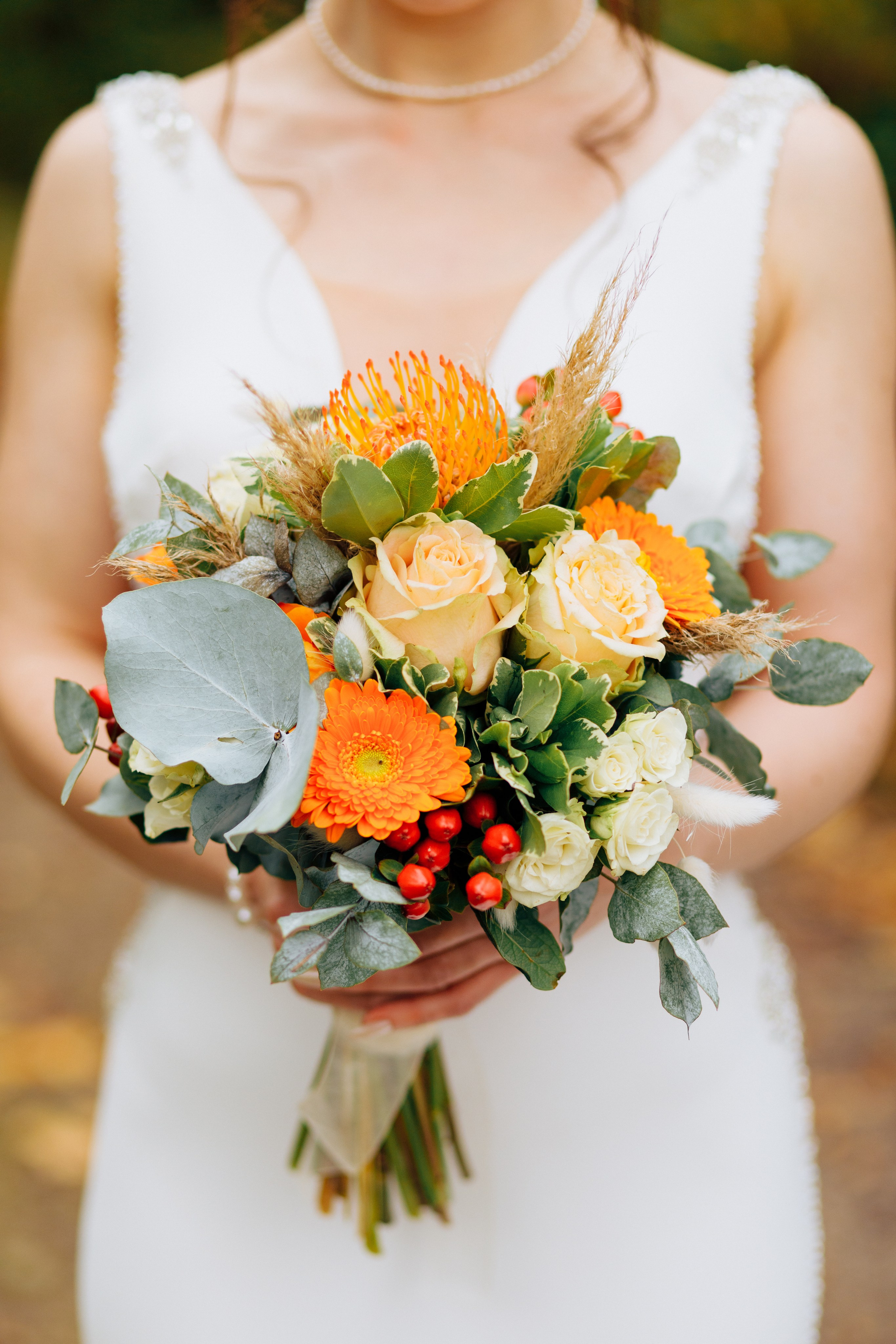Der rustikale Herbsthochzeitsstrauß der Braut in warmen Orangetönen.