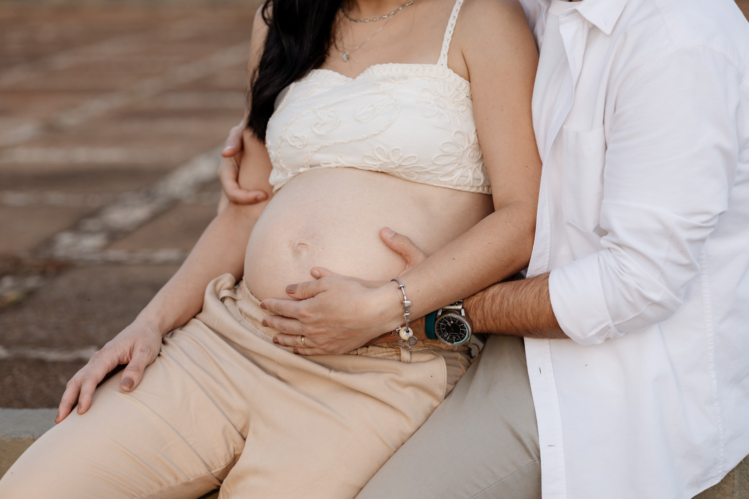 Detalhe da barriga e mãos do casal em ensaio gestante
