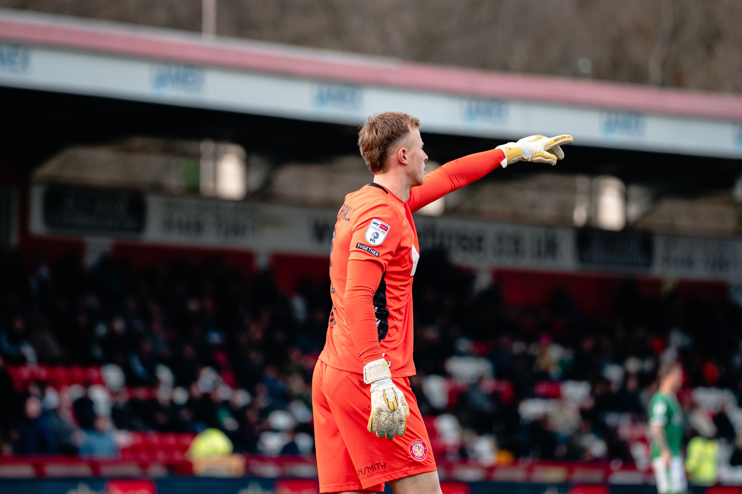 Stevenage player in an orange kit walking during the League One match against Stockport County.