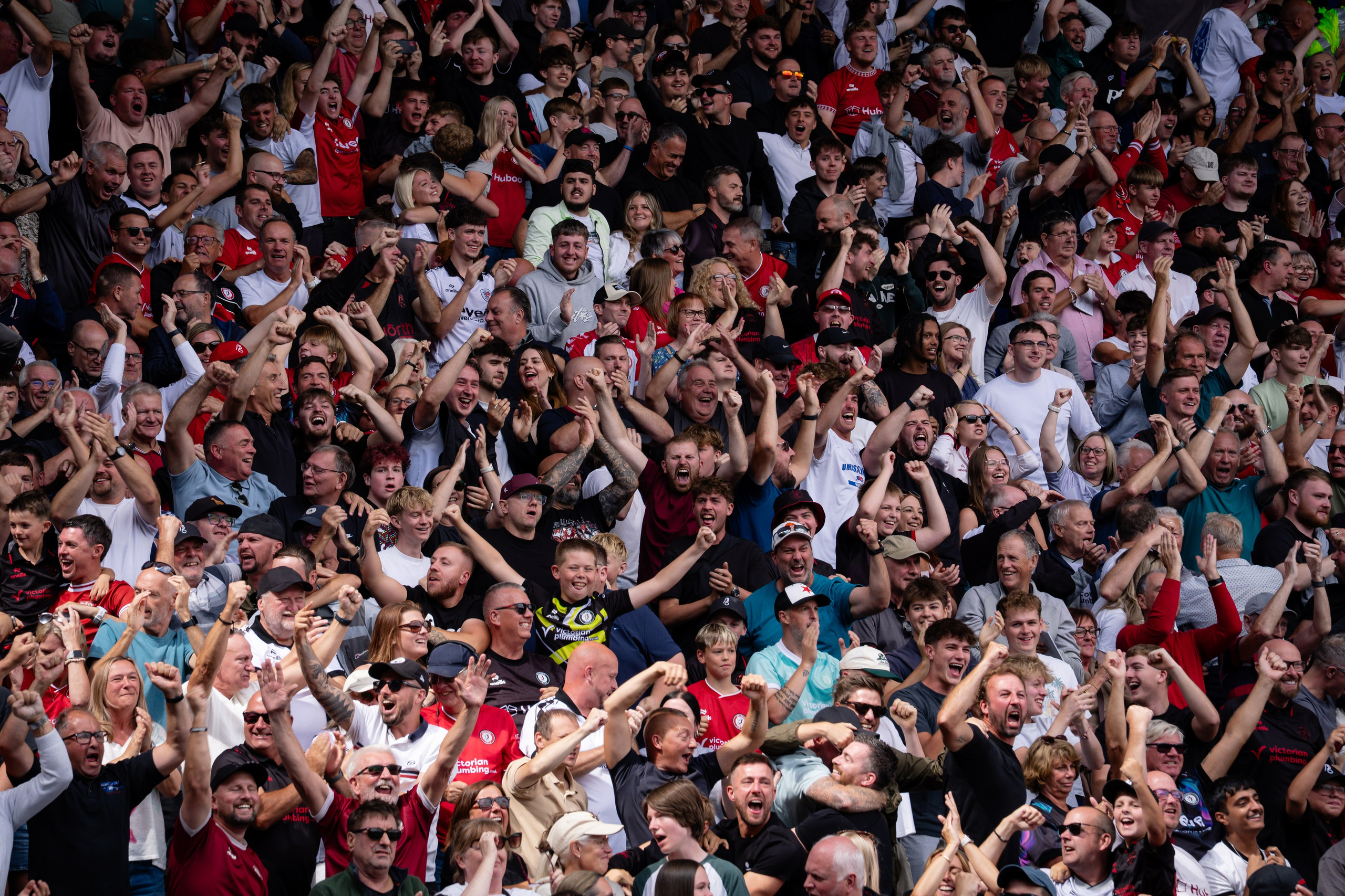 Football supporters celebrating together in a packed stand during a professional match.