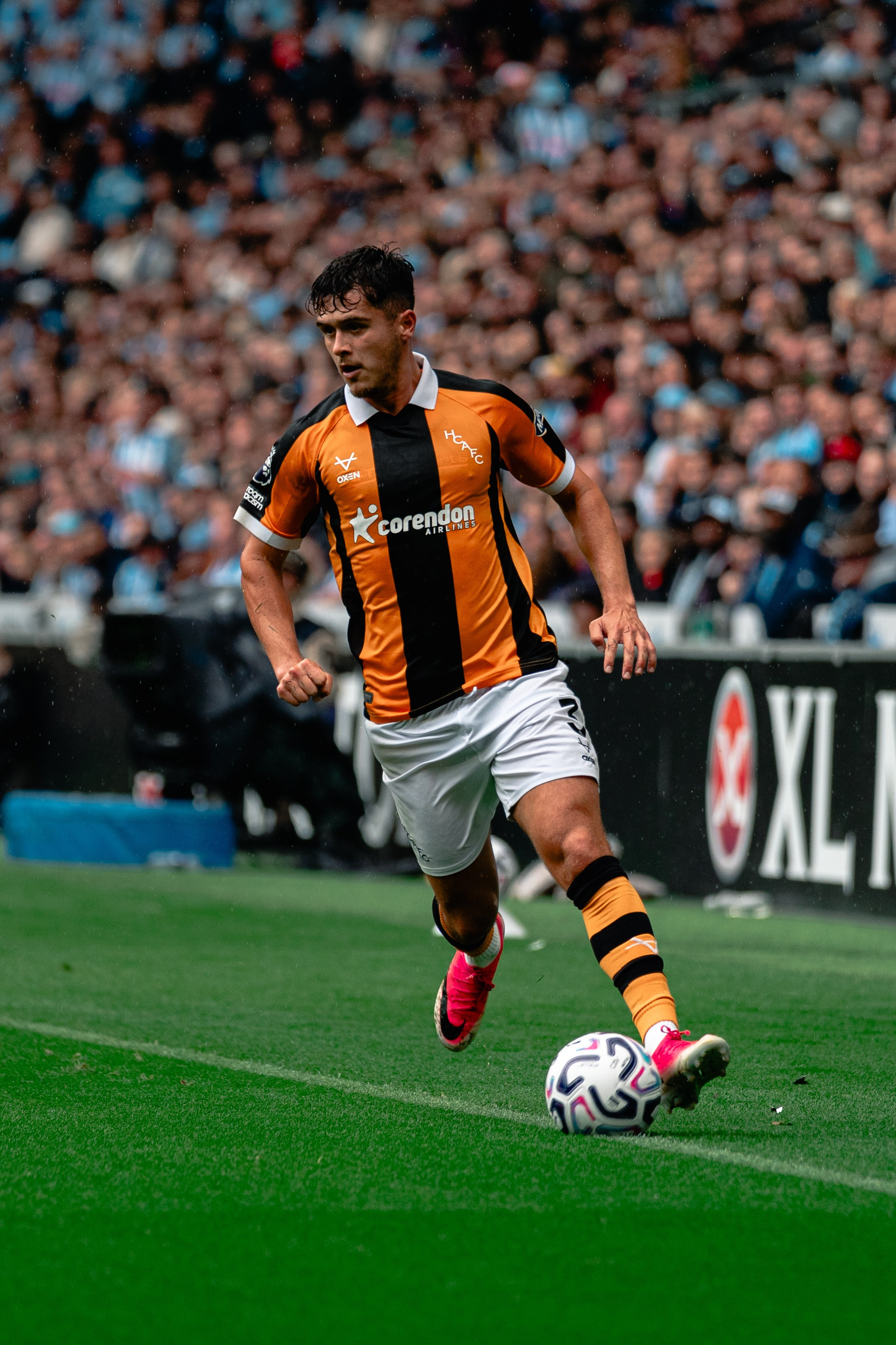 Hull City player carrying the ball down the pitch during a professional football match.