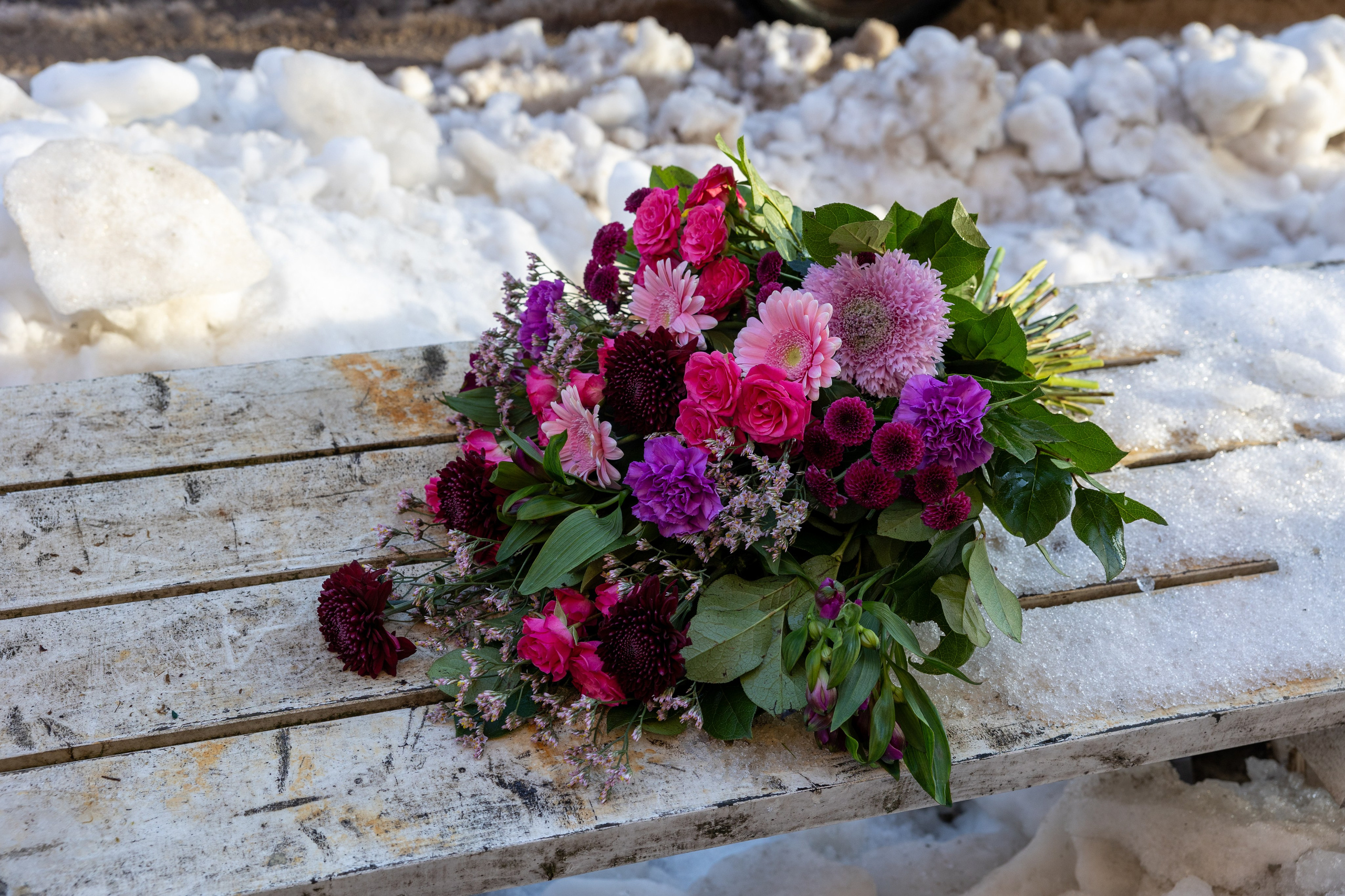 En let og luftig bårebuket, hvor blomsterne er bundet i liggende position. Hver blomst fremhæves smukt med varierede grønt imellem. Bårebuketten er bundet med pink, hvilket lyser ethvert kirkegulv i enhver sæson.