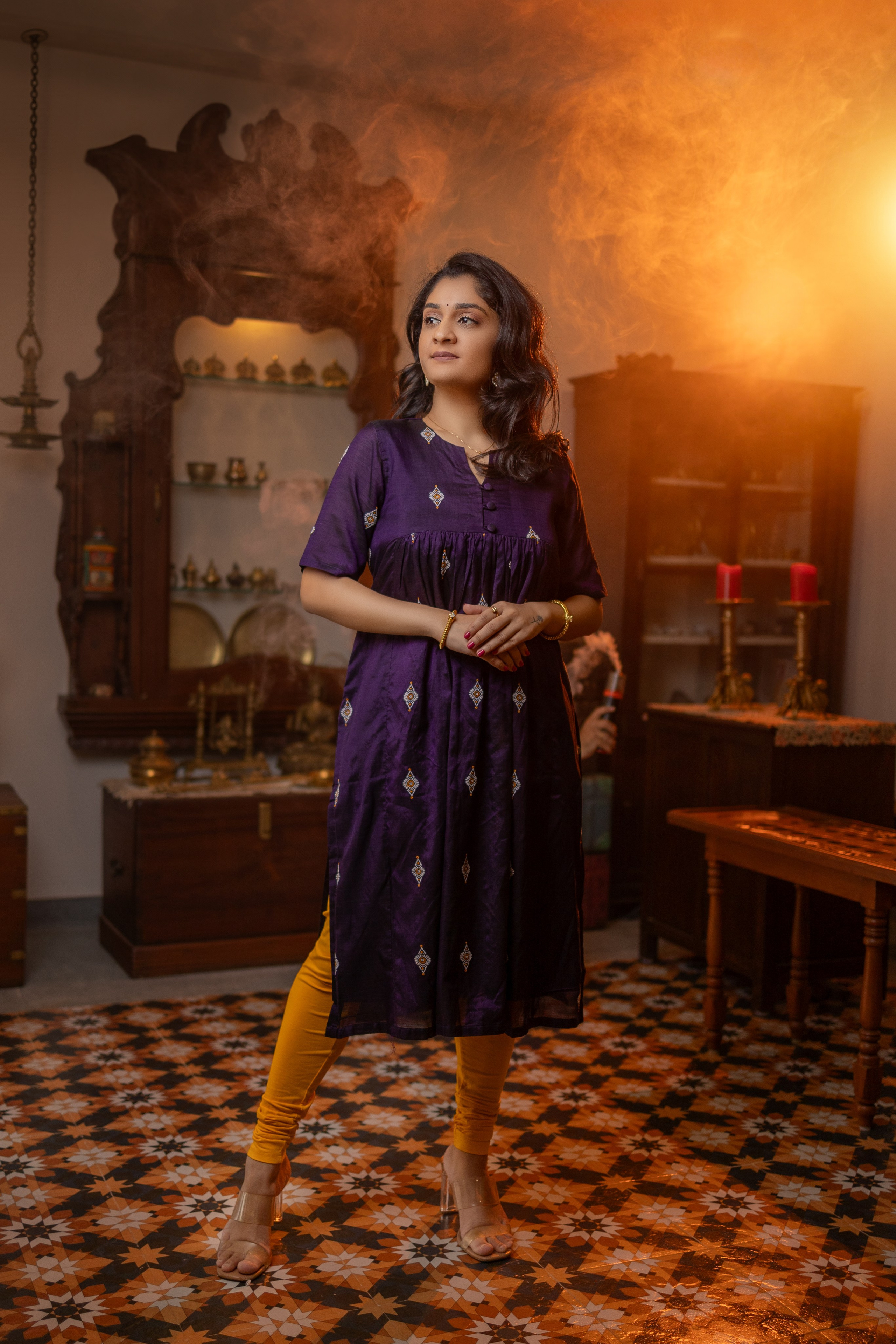 professional indoor portrait of a woman wearing a purple kurta and yellow leggings posing in an antique-styled room in Malleshwaram, Bengaluru
