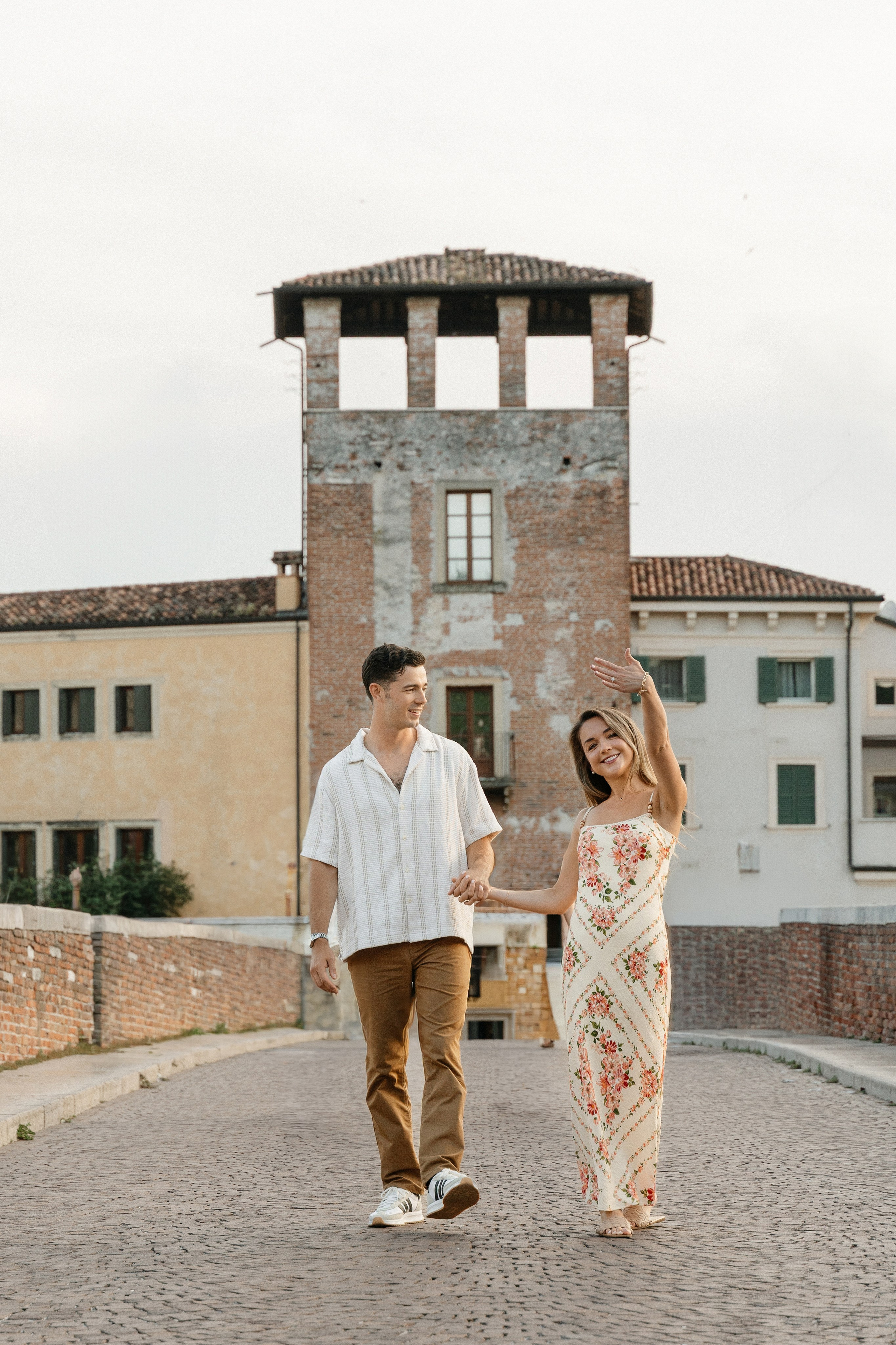 Couple celebrating their engagement while walking through the historic streets near Ponte Pietra