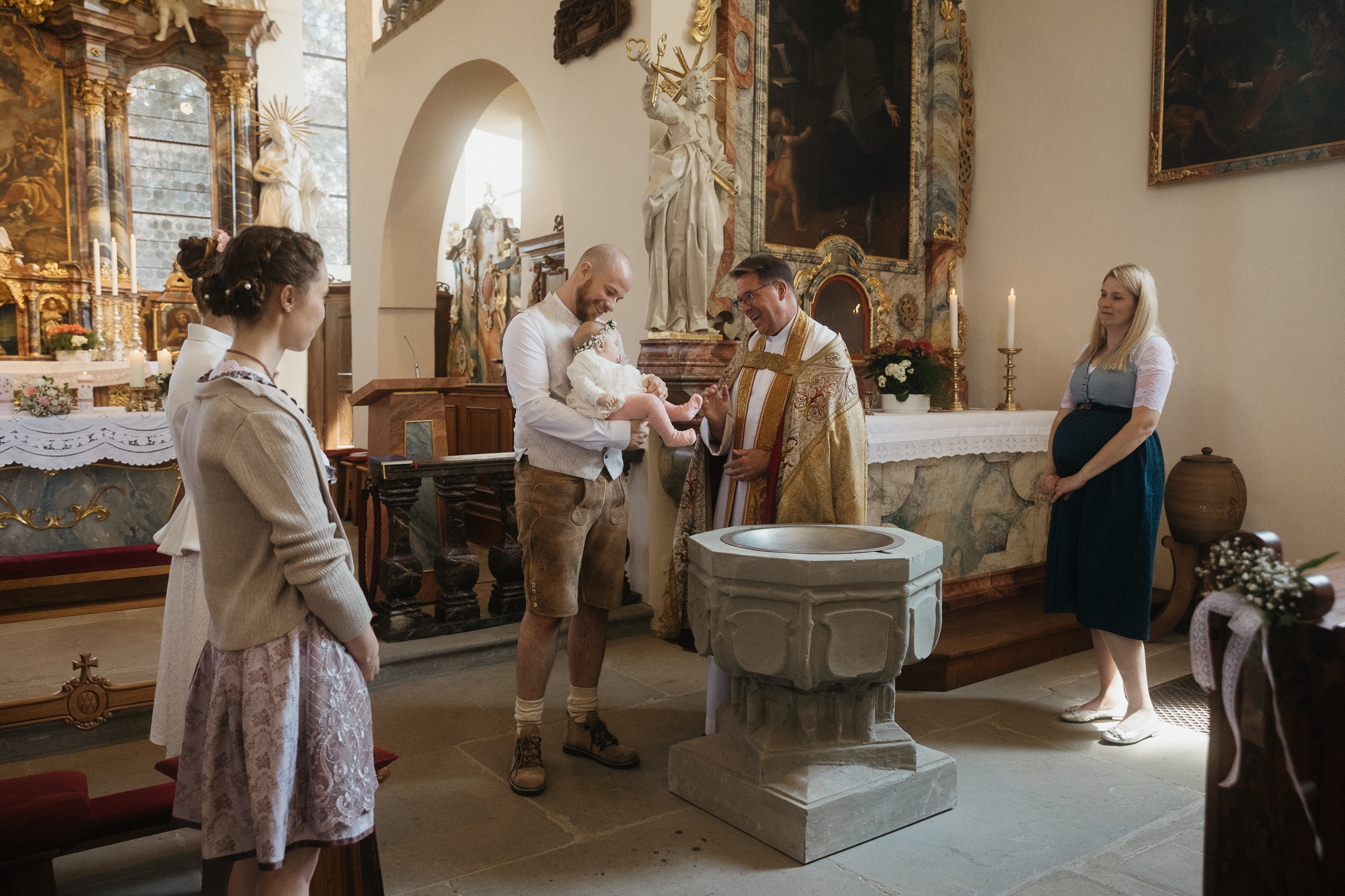 Vater hält Baby am Taufbecken, Kirche Heiligenberg