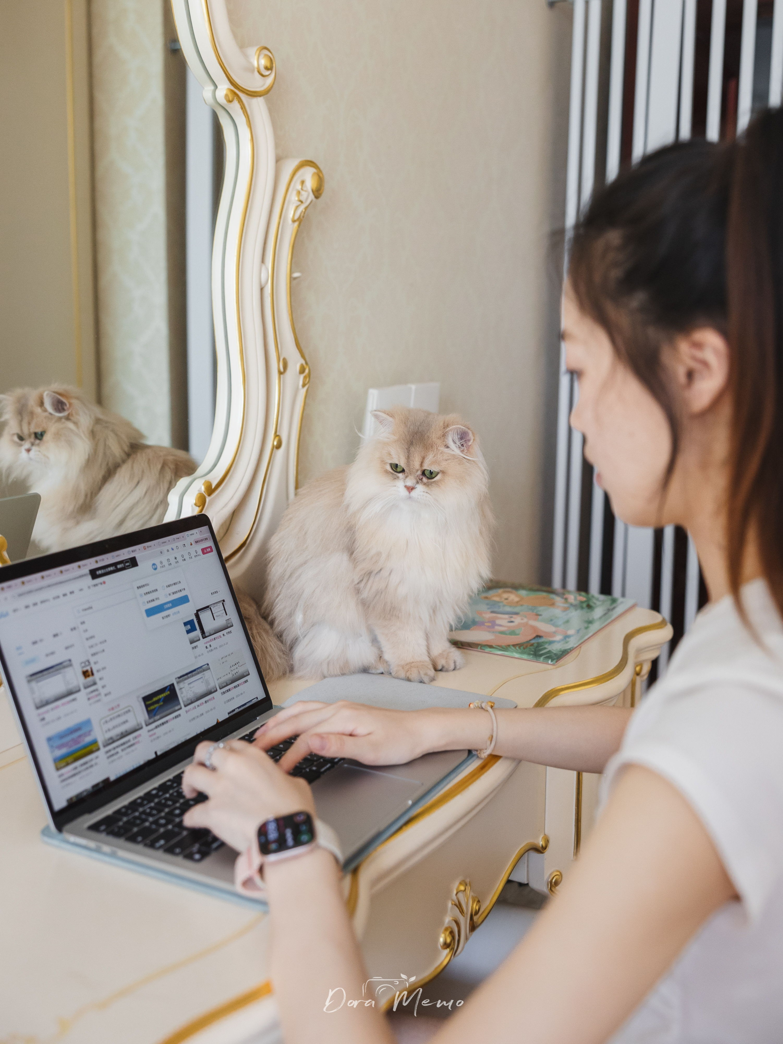 Two cats keep their mom company while she works on a laptop at home.