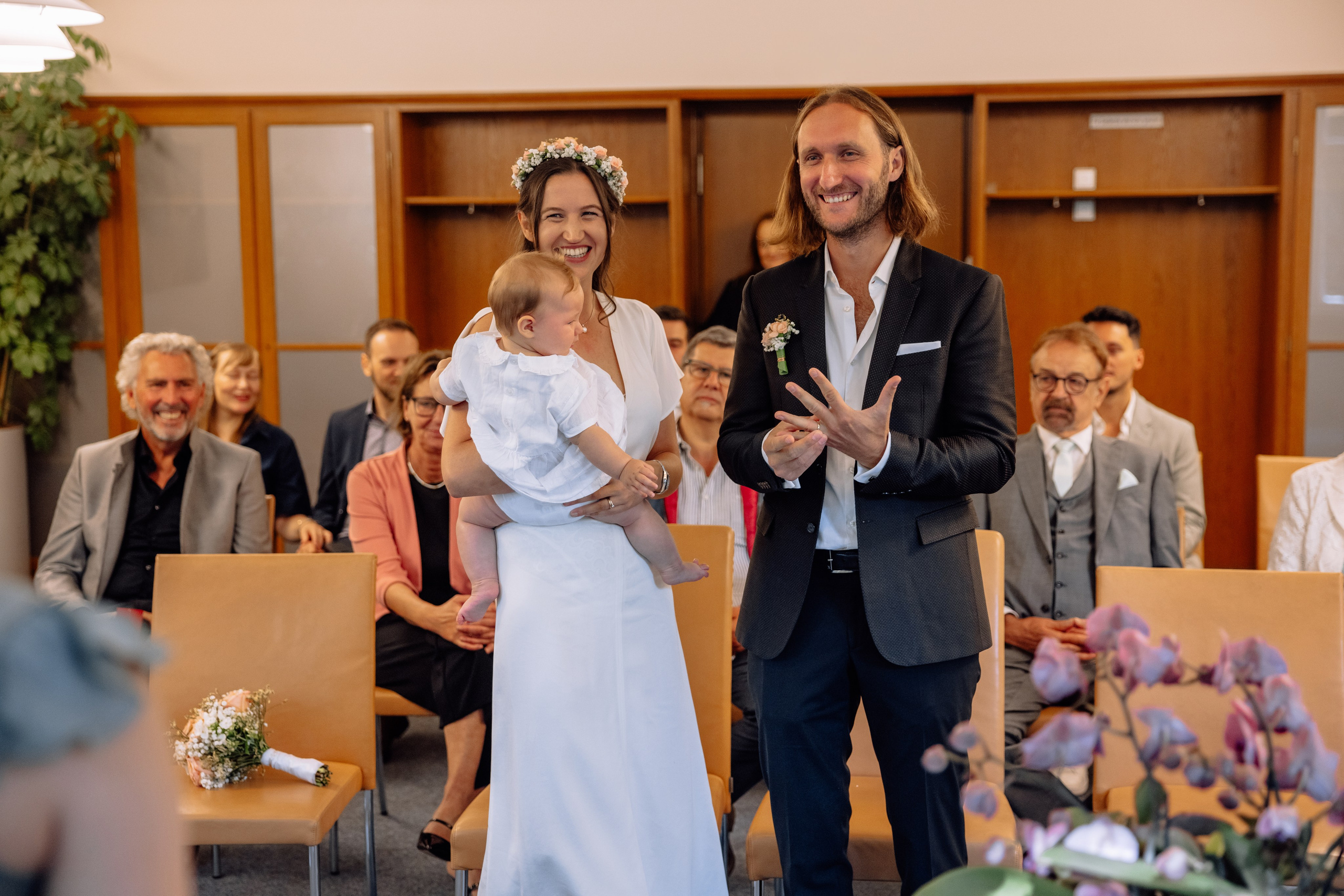 Eltern halten Baby während der Zeremonie – Gäste im Hintergrund, Standesamt Mandlstraße 14
