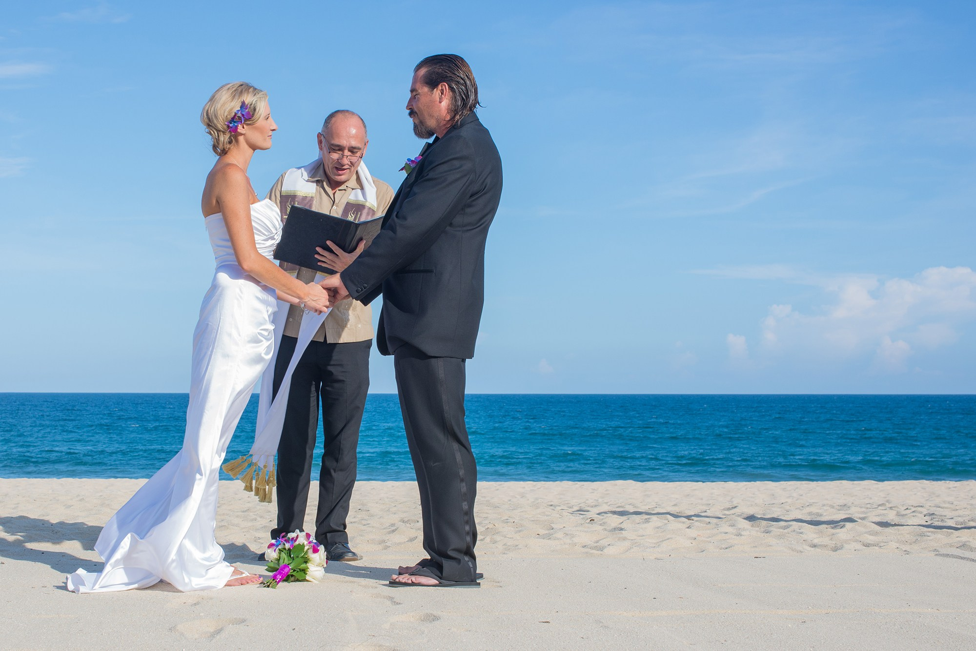 Civil wedding ceremony in Los Cabos – couple standing by the sea with officiant, romantic beach wedding photography in Baja California Sur