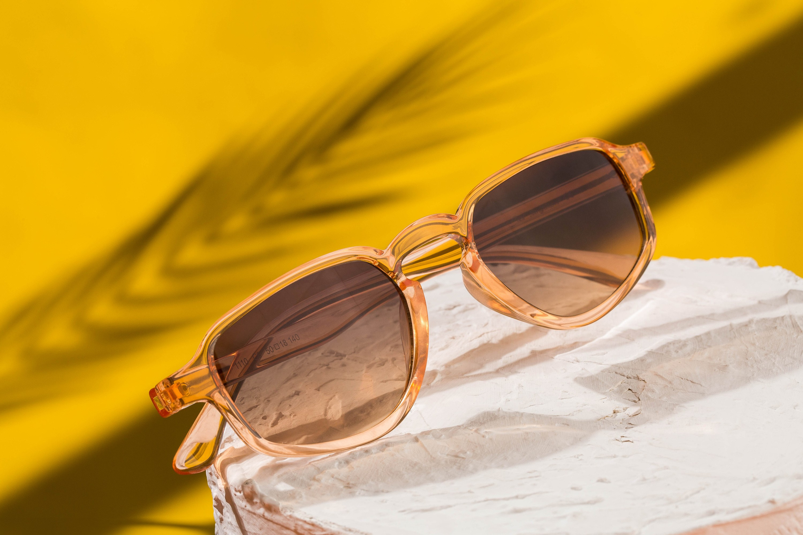 kreativ eynək fotosu sarı fon üzərinə düşən palma kölgəsi yay abu havası yaradır