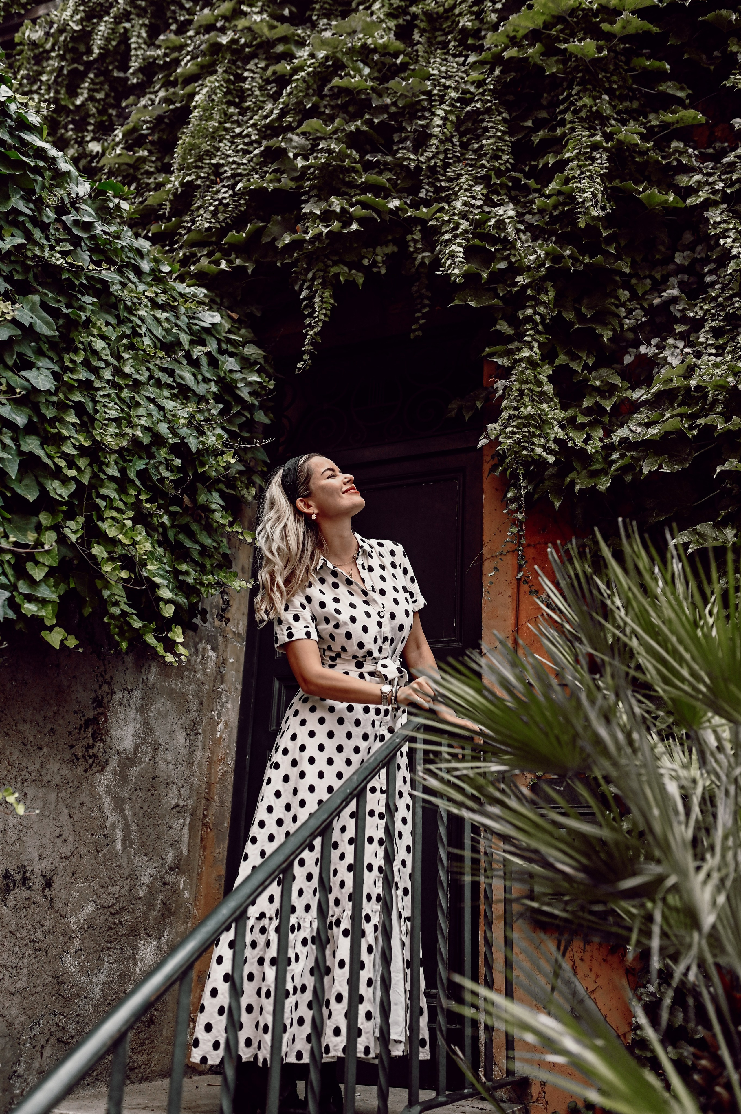 A smiling woman in a polka-dot dress gazes upward in Trastevere.