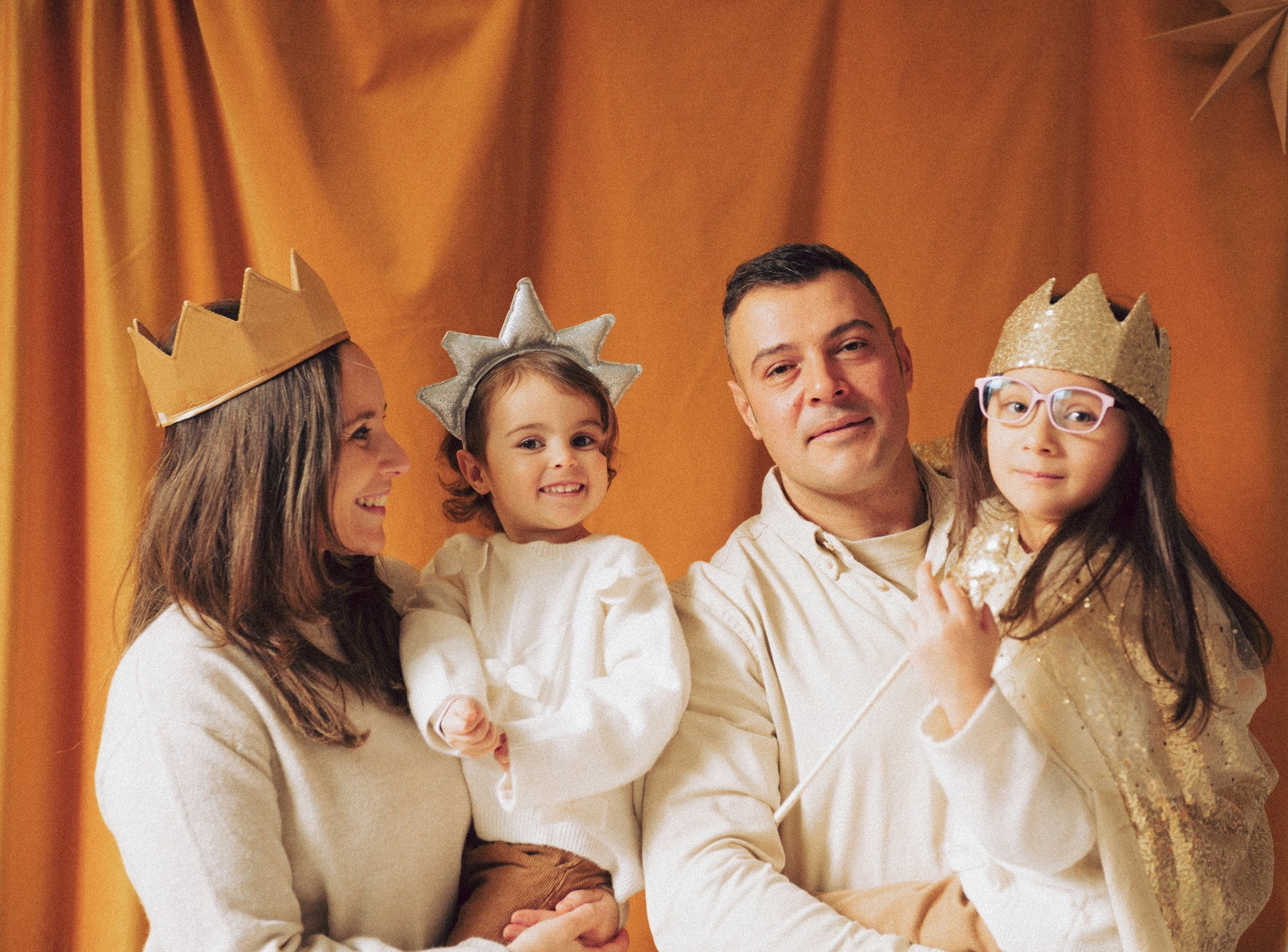 Family with two children wearing festive crowns during a Christmas studio photoshoot. A warm and natural family portrait captured during a Christmas photo session in a daylight studio in Milan. Parents and children wear festive crowns and smile together, creating genuine and emotional memories. Ideal for families looking for a Christmas photoshoot in Milan, natural family portraits, children’s Christmas photography, and cozy studio holiday sessions. Christmas photoshoot Milan, family photographer Milan, kids Christmas photo session, natural family portraits, holiday studio session.