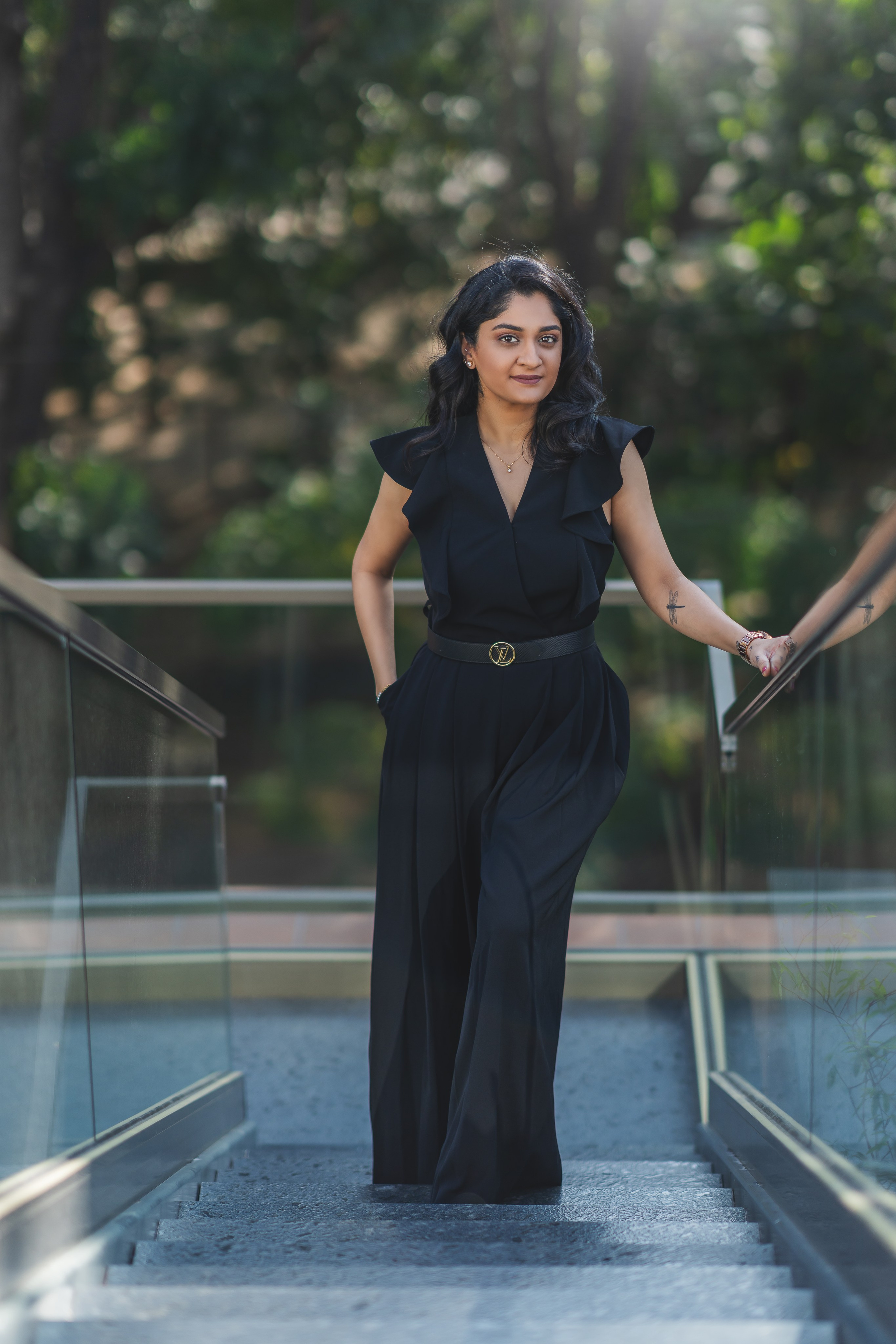 professional outdoor portrait of a woman in a black top and trousers walking down a modern staircase in Malleshwaram, Bengaluru