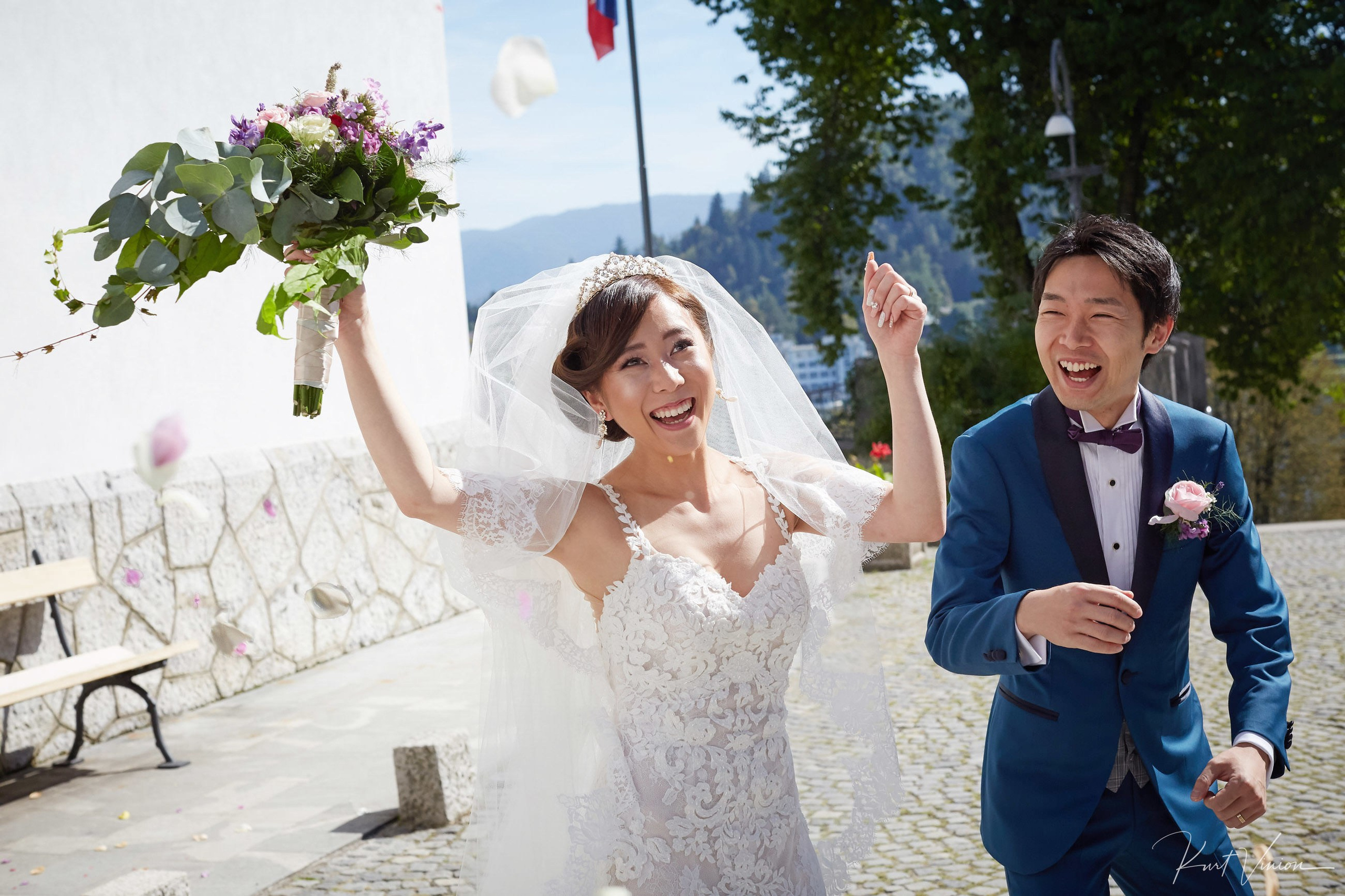 Joyful bride celebrating bouquet clutched groom laughing post-ceremony.