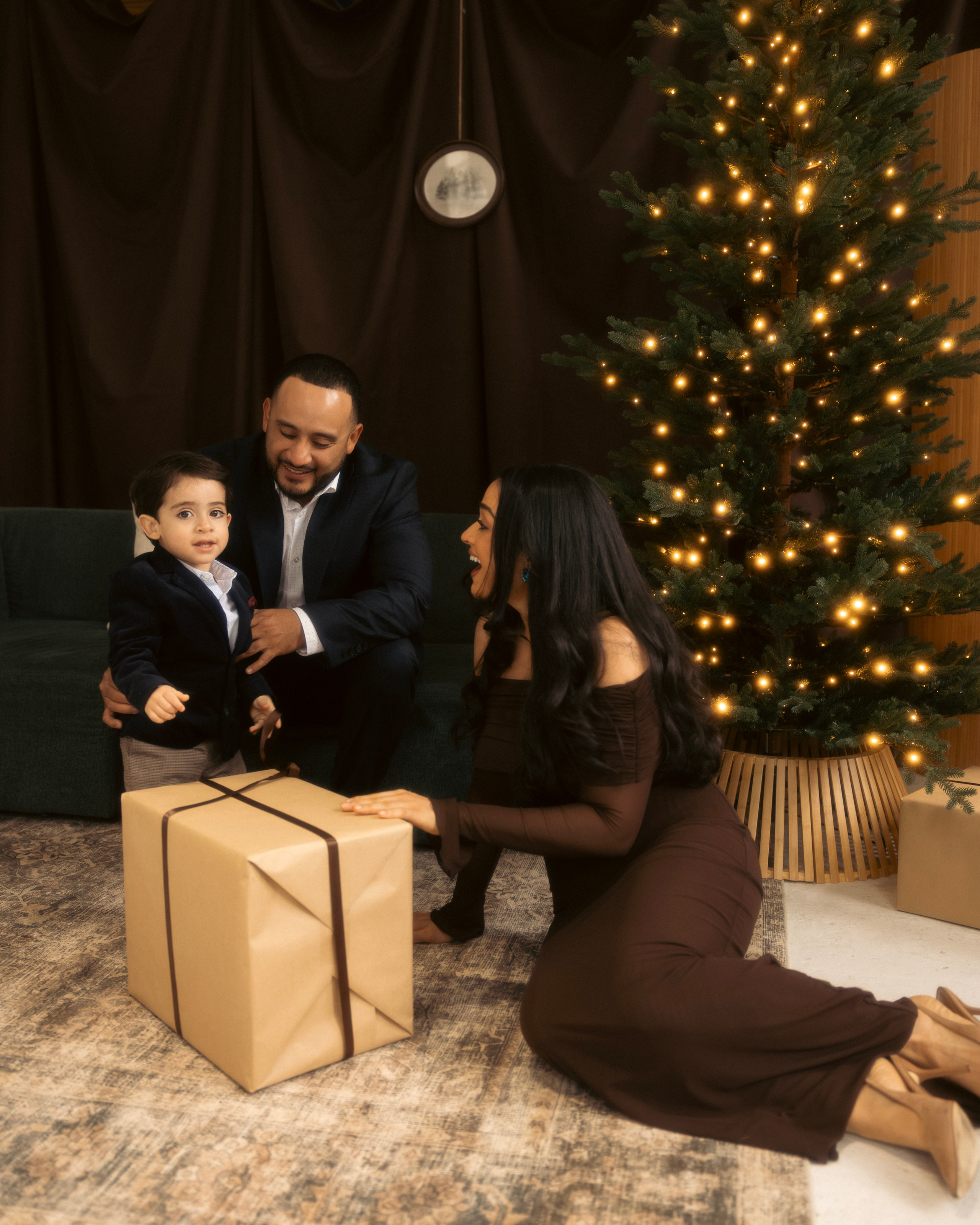 Mom and dad with toddler on studio sofa during Christmas minis
