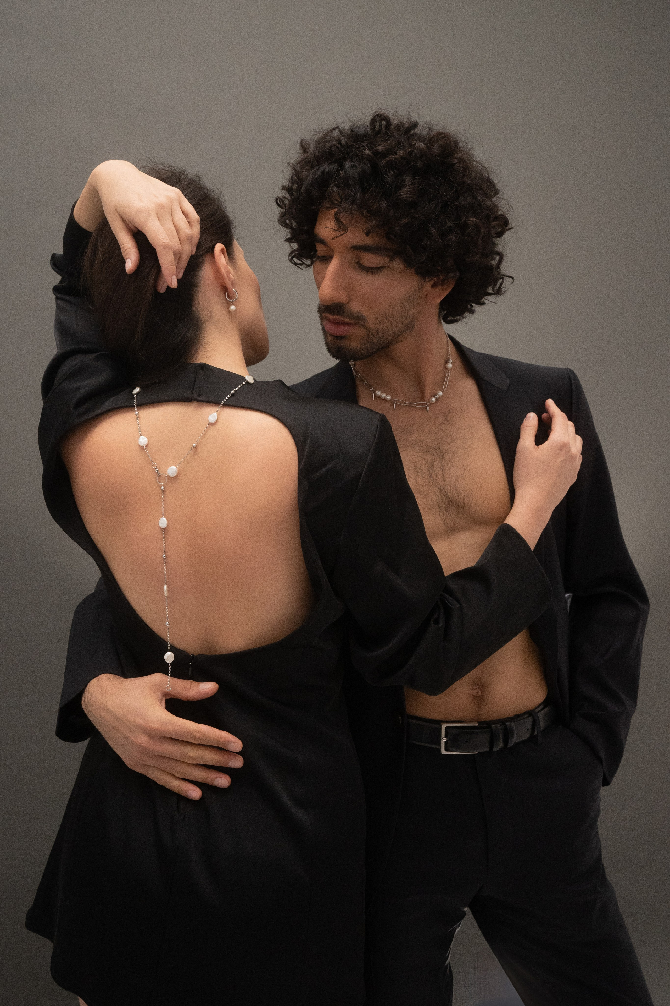 Dos modelos abrazados, collar de perlas visible