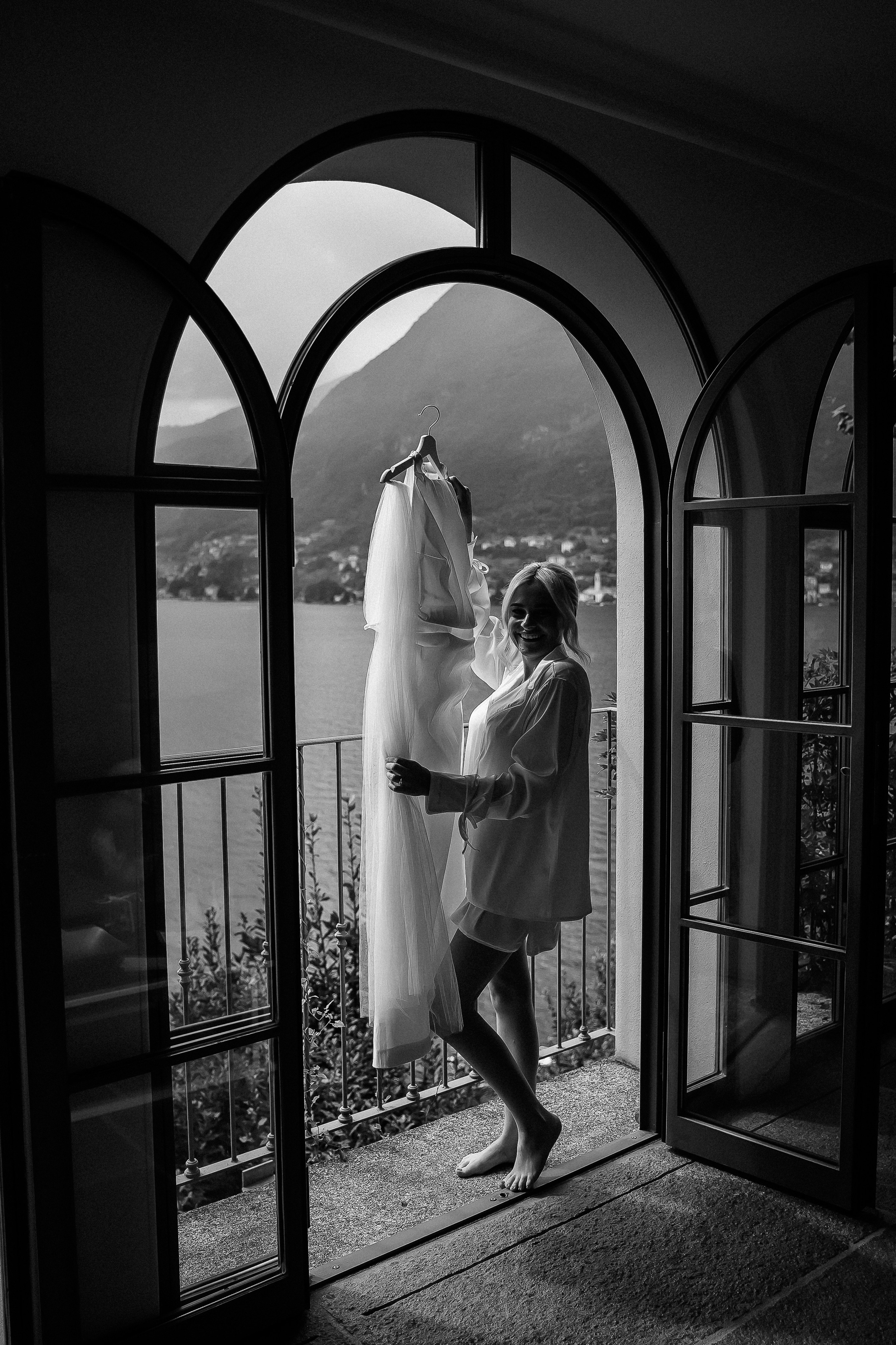 Black and white photo of a bride adjusting her wedding dress at Villa Lario, Lake Como, Italy