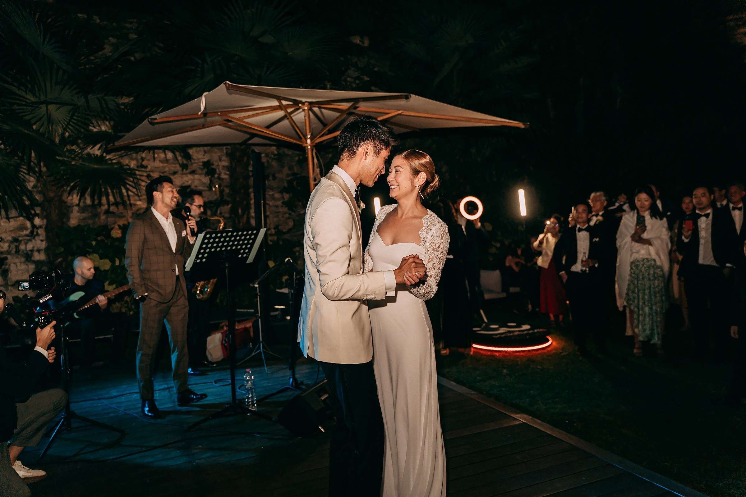 Bride and groom share their first dance under warm lights, surrounded by guests enjoying the moment.