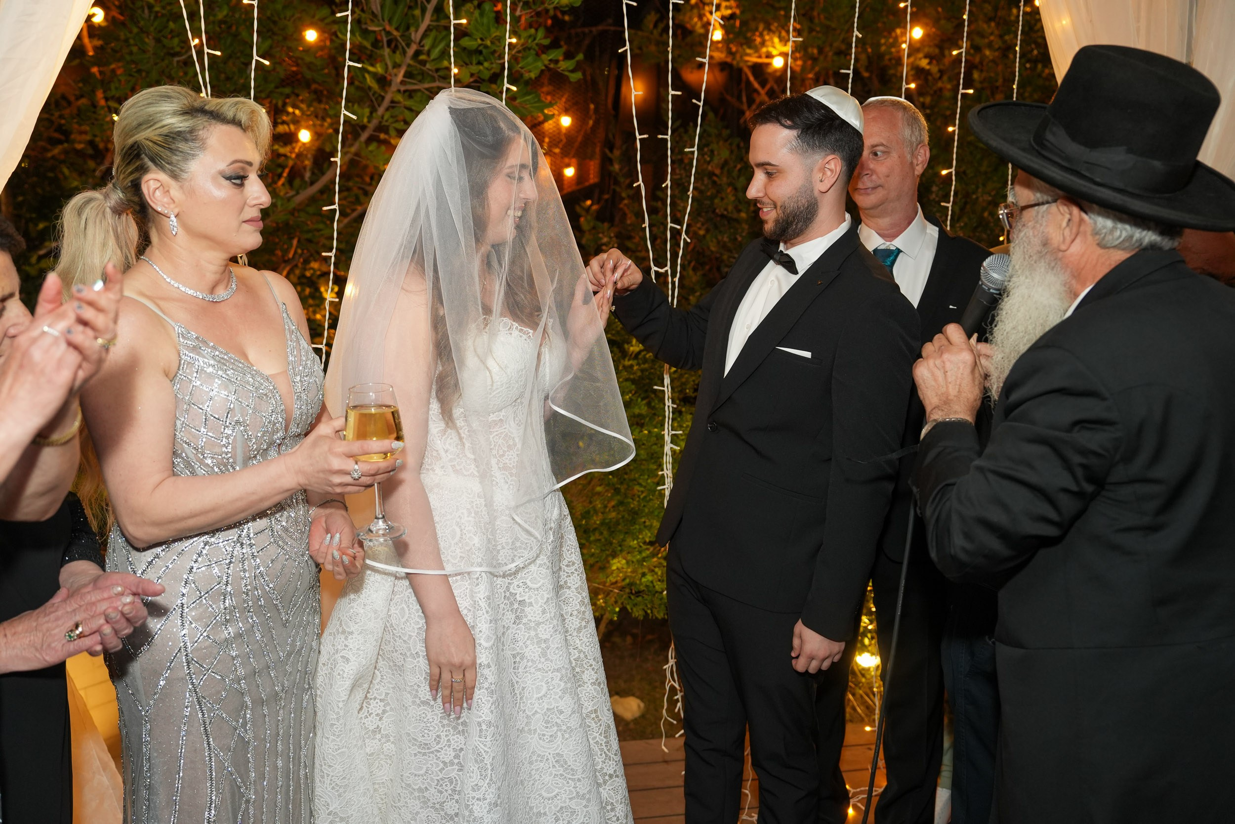 Bride Tzipi and groom Ron holding hands under the Chuppah with their parents looking on at 88 Event Garden in Emek Hefer, Israel
