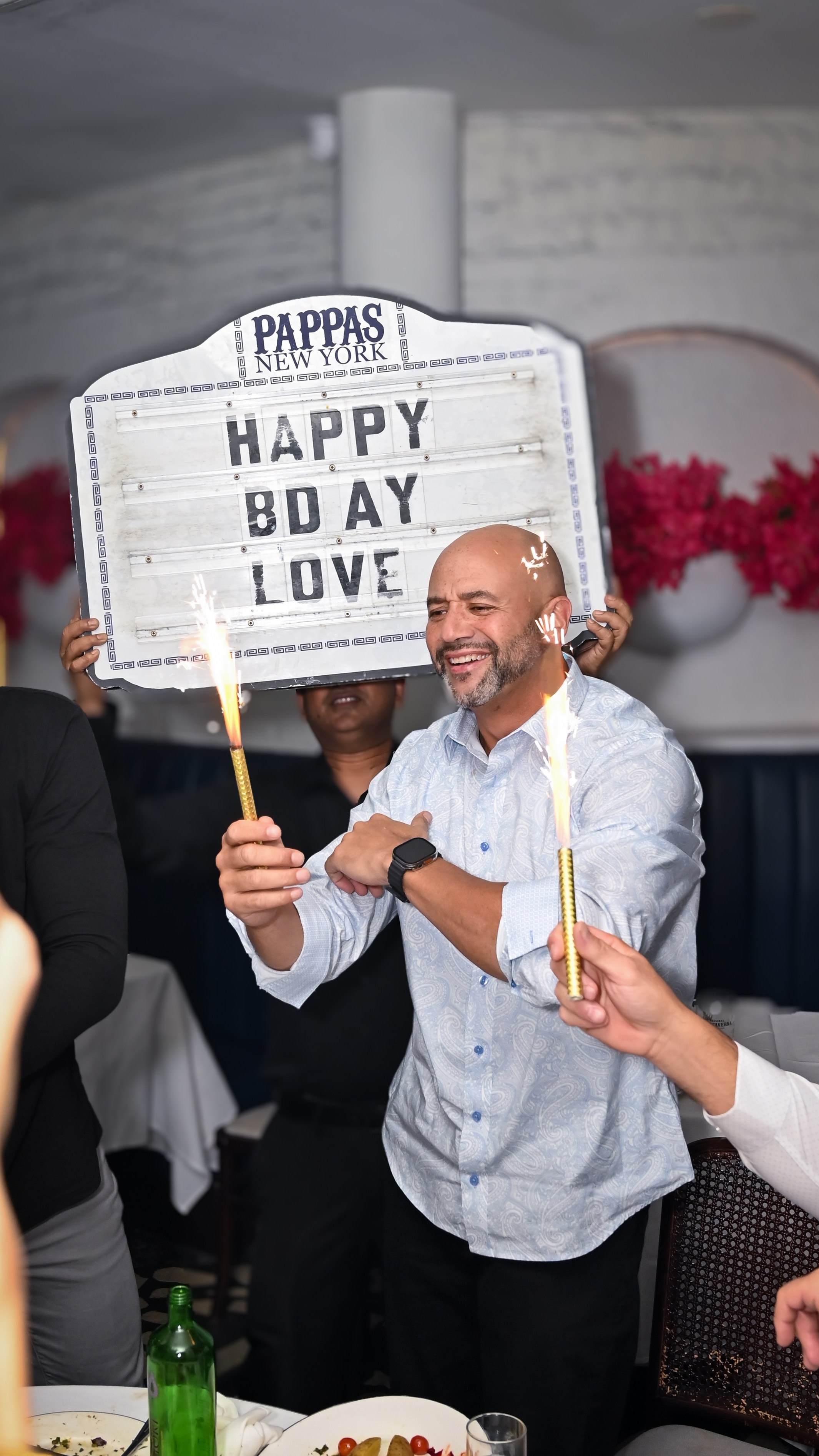 Man holding a “Happy Birthday” sign at a restaurant party, NYC birthday event photography.