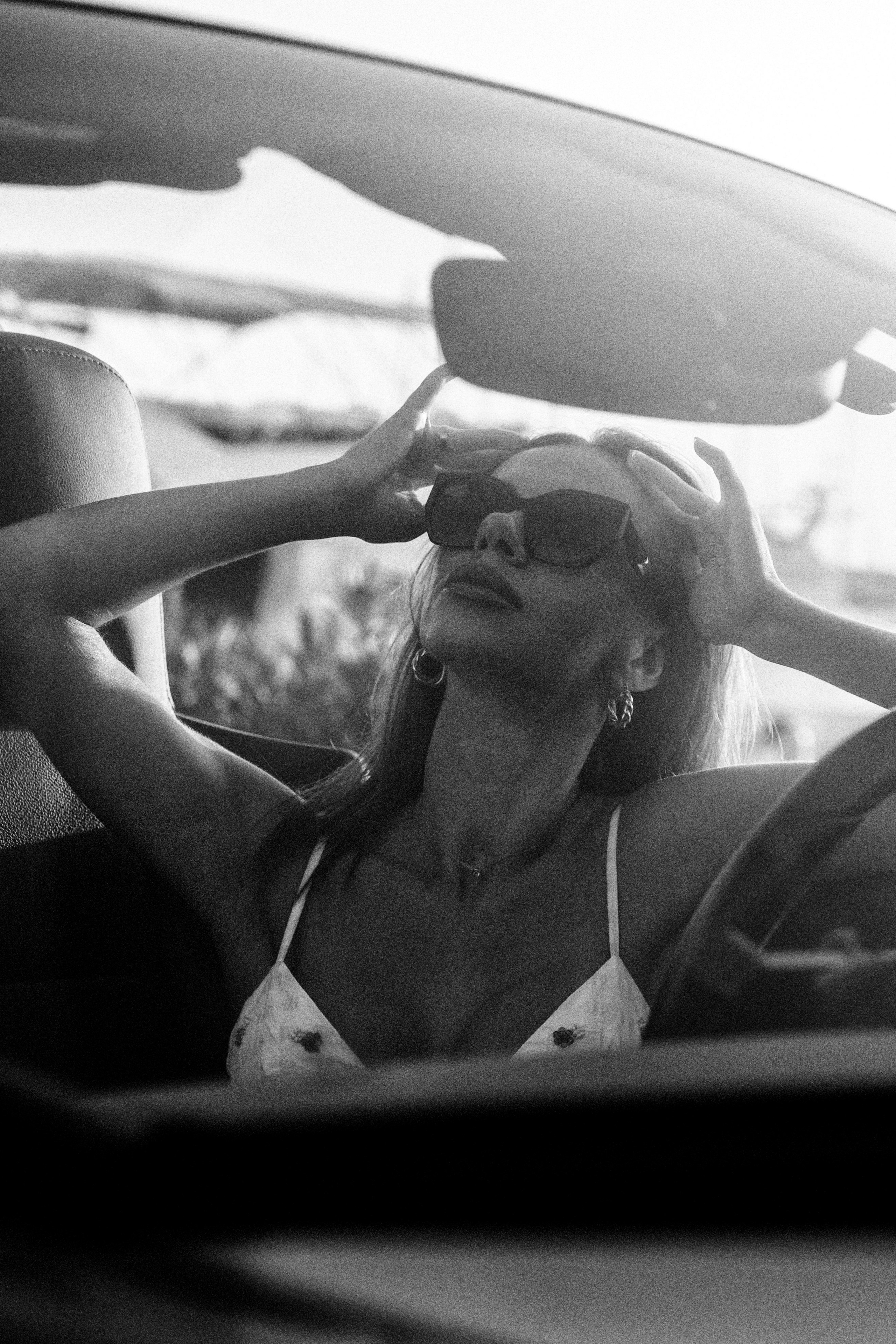 Женская фотосессия в Валенсии, Испания, со стильным чёрно-белым портретом женщины в солнцезащитных очках в кабриолете, снятым в естественном свете с кинематографичным fashion-настроением — идеально для женской портретной фотографии, лайфстайл-съёмок, редакционных портретов и современных женских фотосессий в Валенсии и по всей Испании.