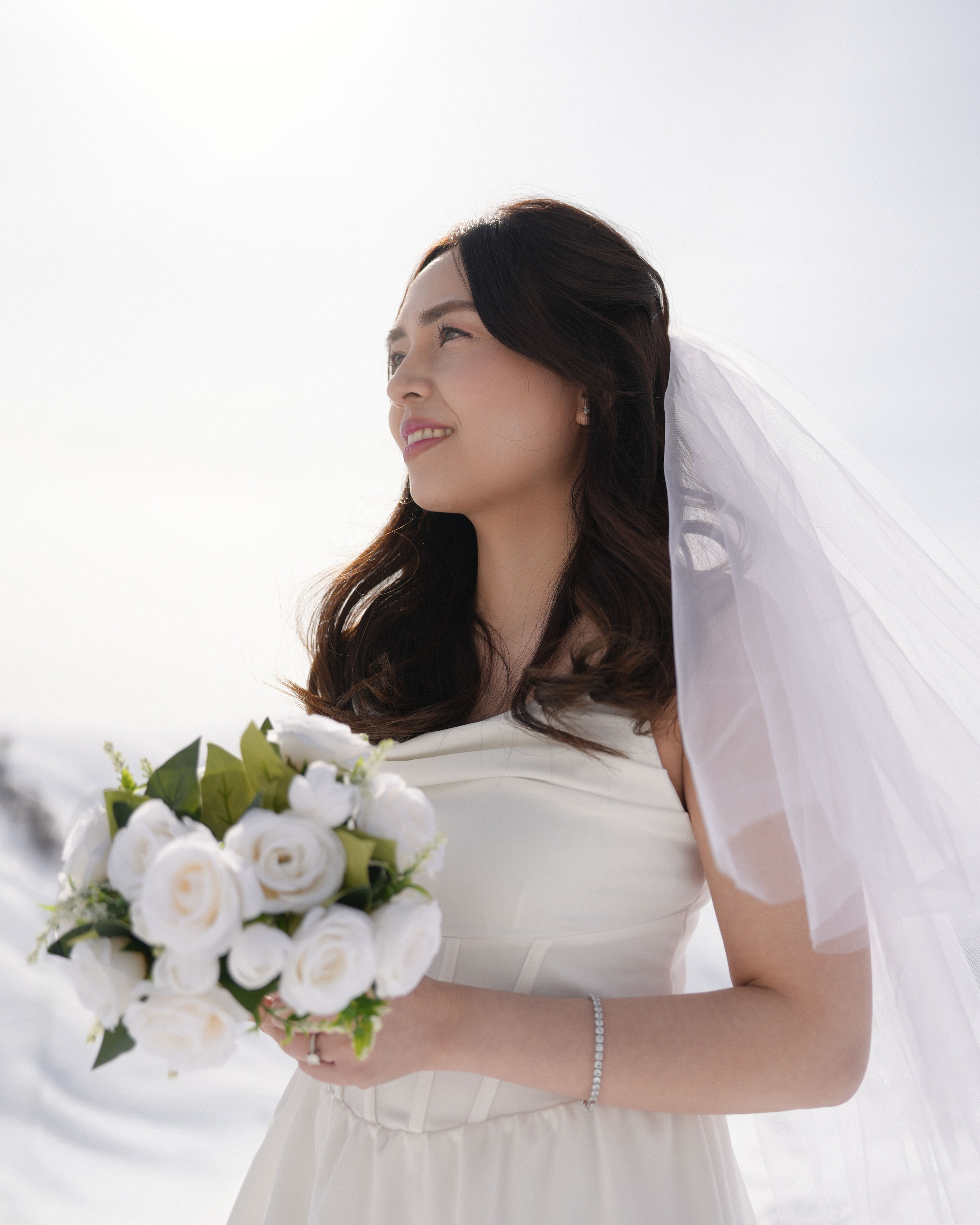 Bride holding bouquet on the mountain slope during winter shoot