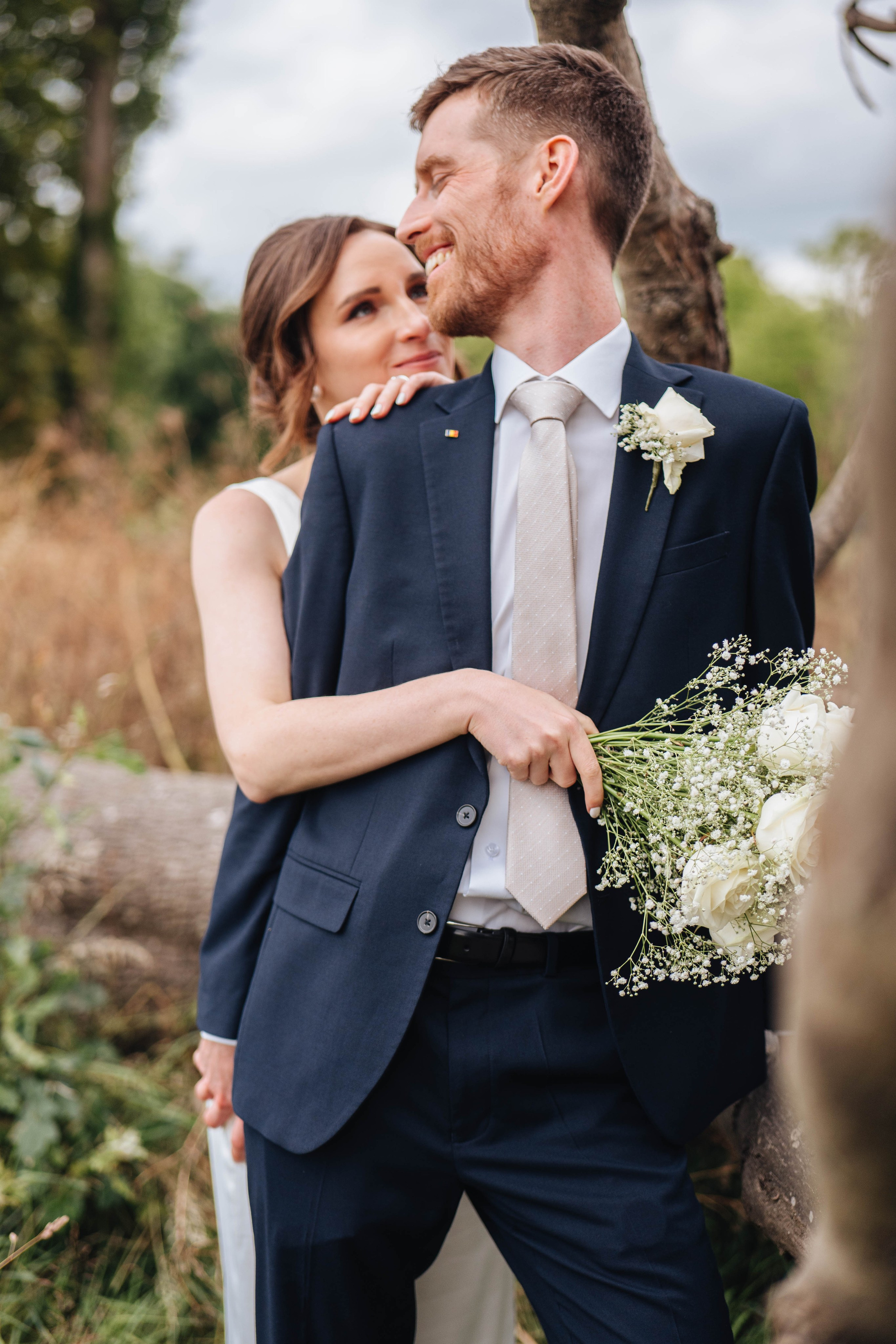 bride hugging the broom from the back and smiling