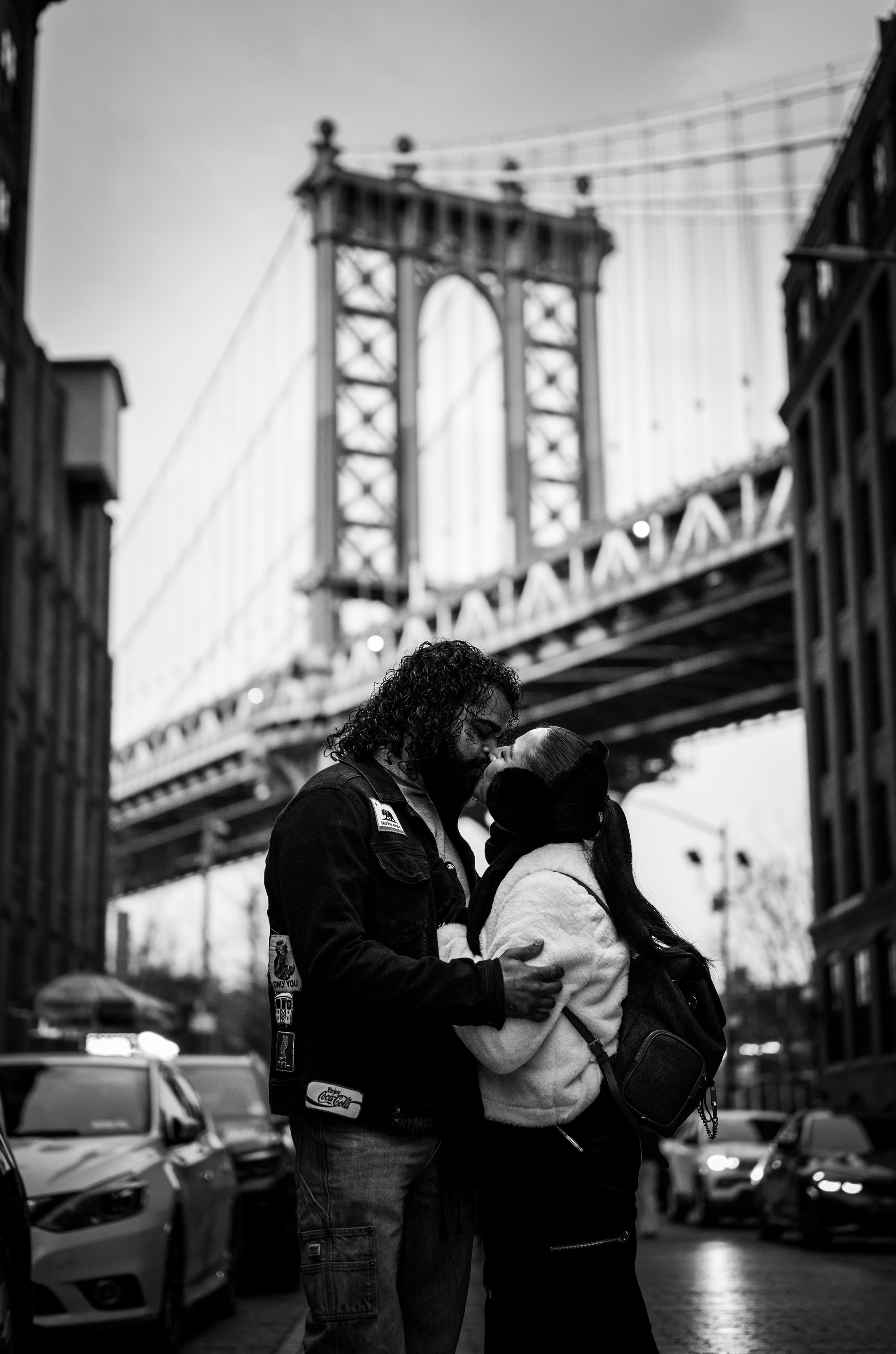 Black and white couple portrait under the Manhattan Bridge in DUMBO Brooklyn, classic New York City street photography.