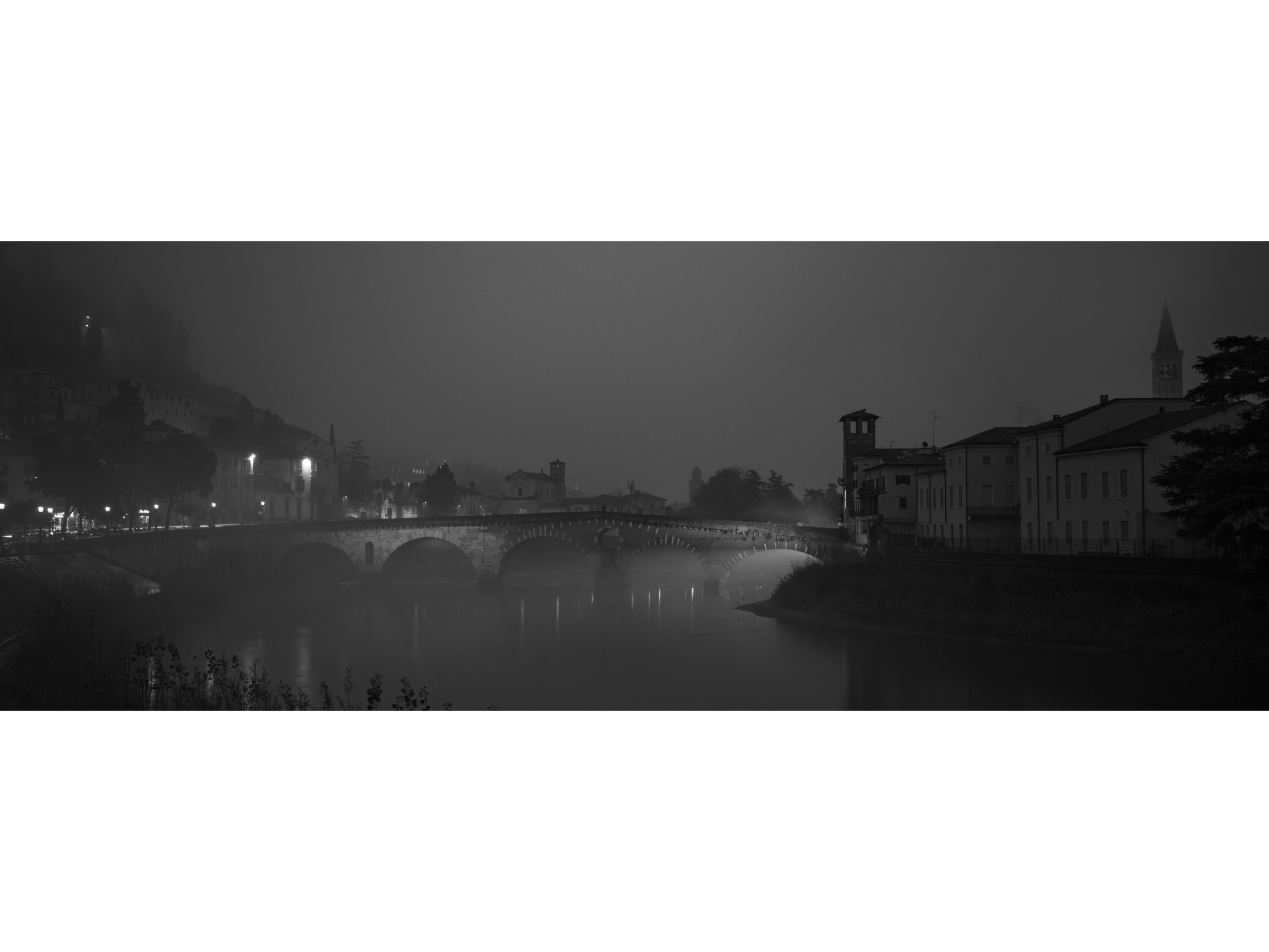 Moody fine art photography of Verona in winter fog. Ponte Pietra and the Adige river dissolve into atmospheric minimalism. Timeless architectural wall art for collectors and interiors.