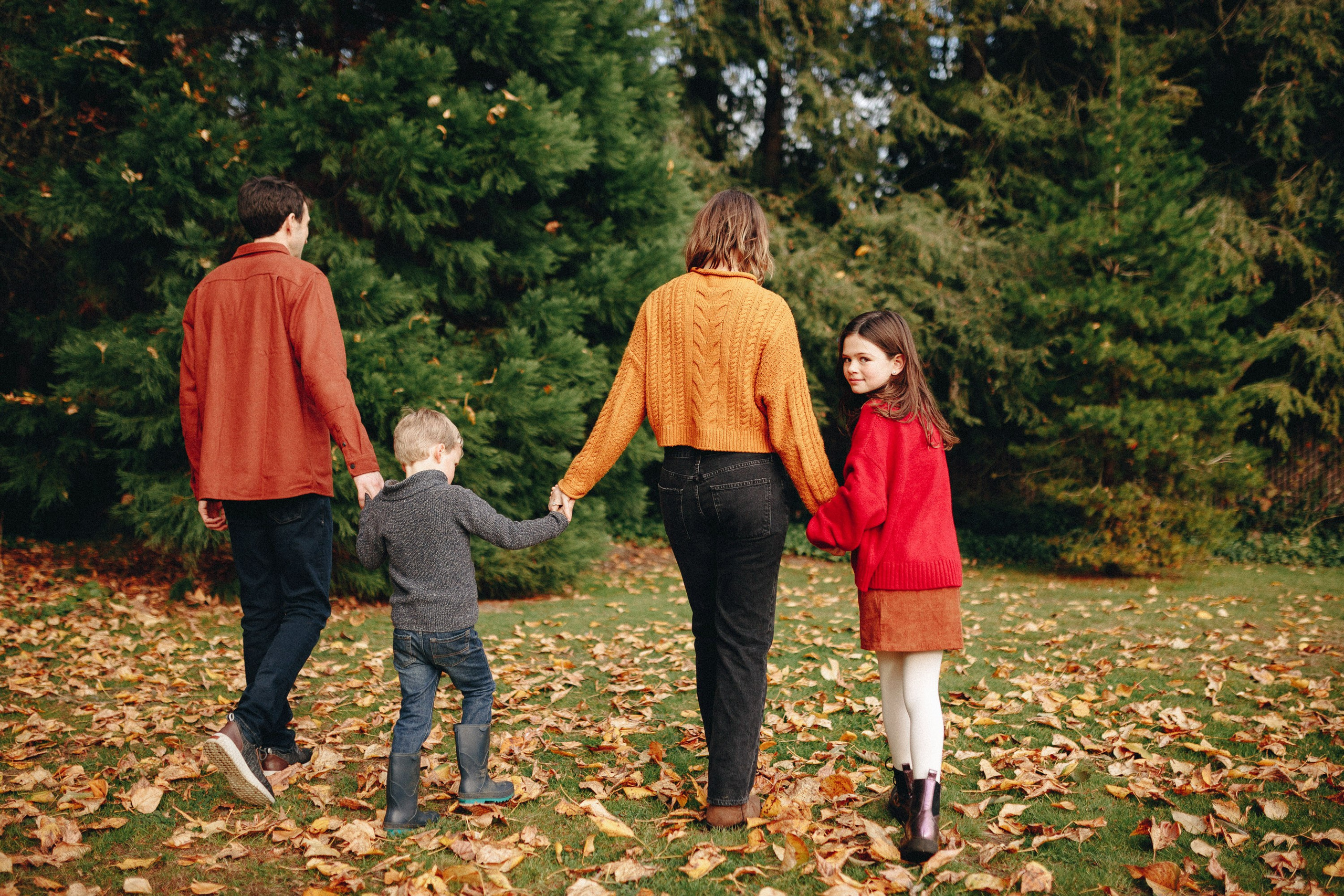Family walking hand in hand through autumn leaves