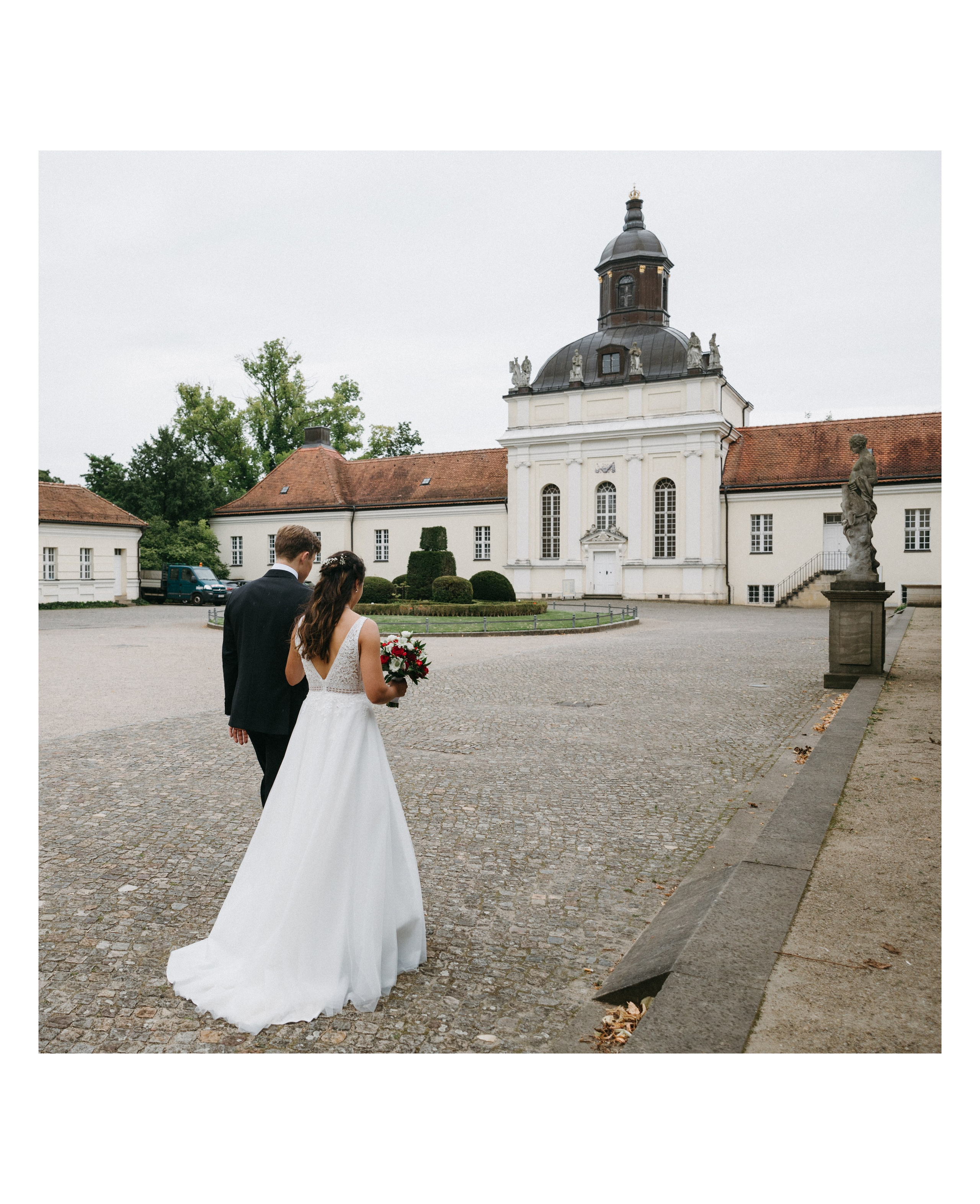 Braut und Bräutigam spazieren im Schlosshof von Schloss Köpenick