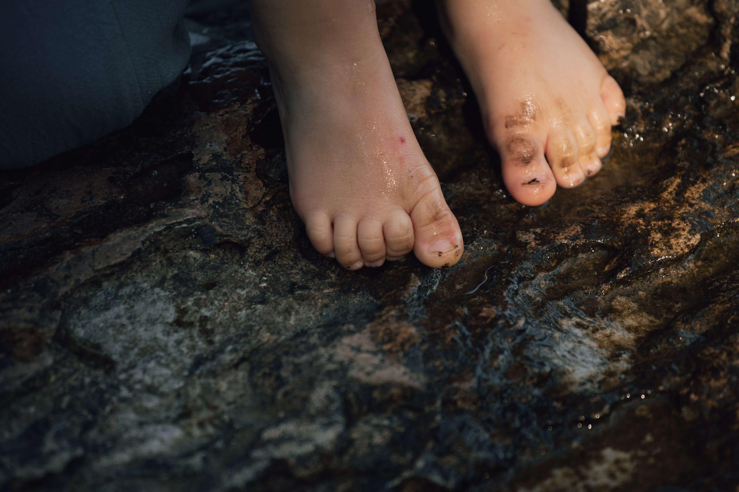 Føtter til barn som hopper fra en liten stein i vannet