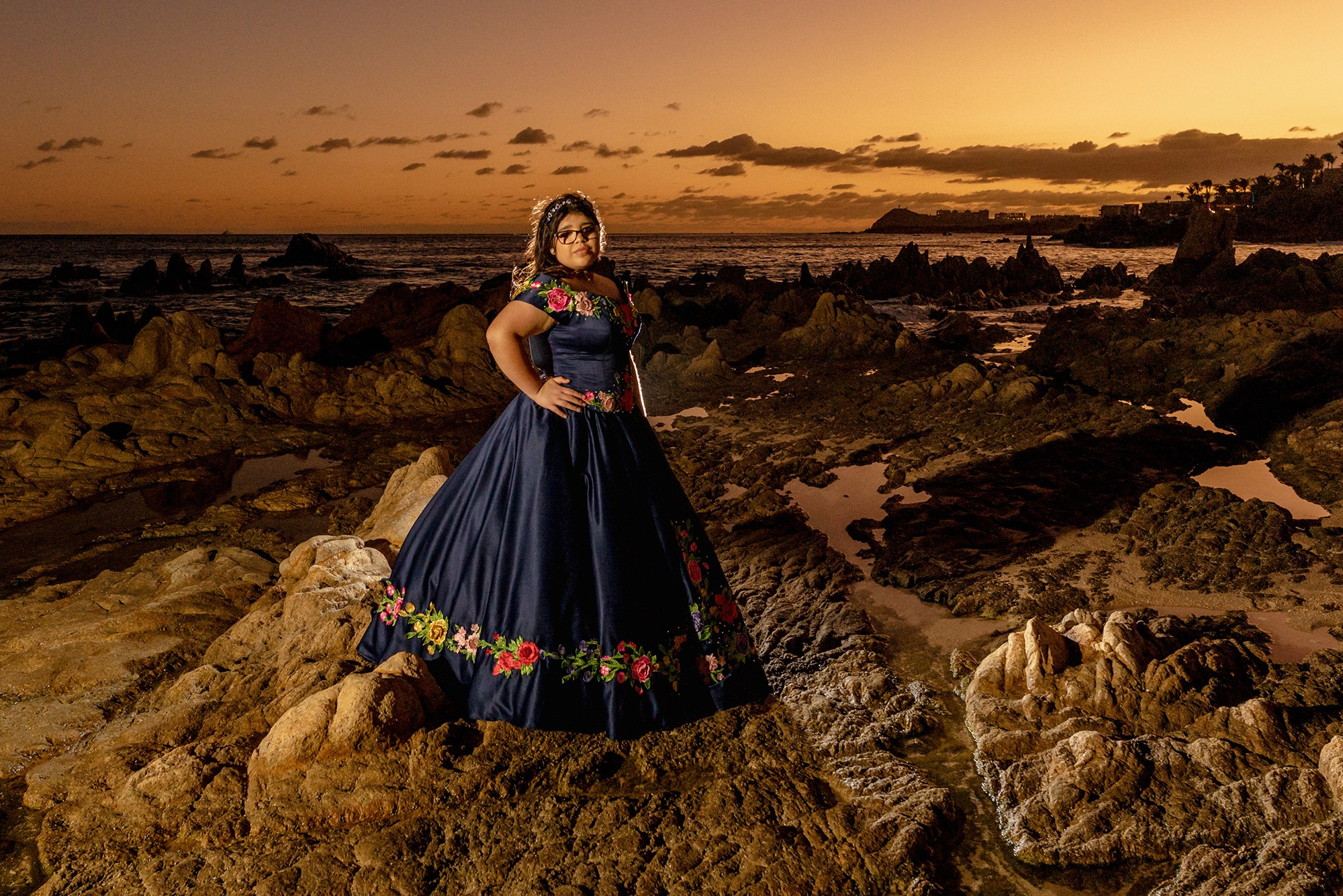 Cabo San Lucas XV años session – artistic portrait of quinceañera in embroidered Mexican blue gown with flowers, photographed at Playa Las Viudas during sunset by destination photographer