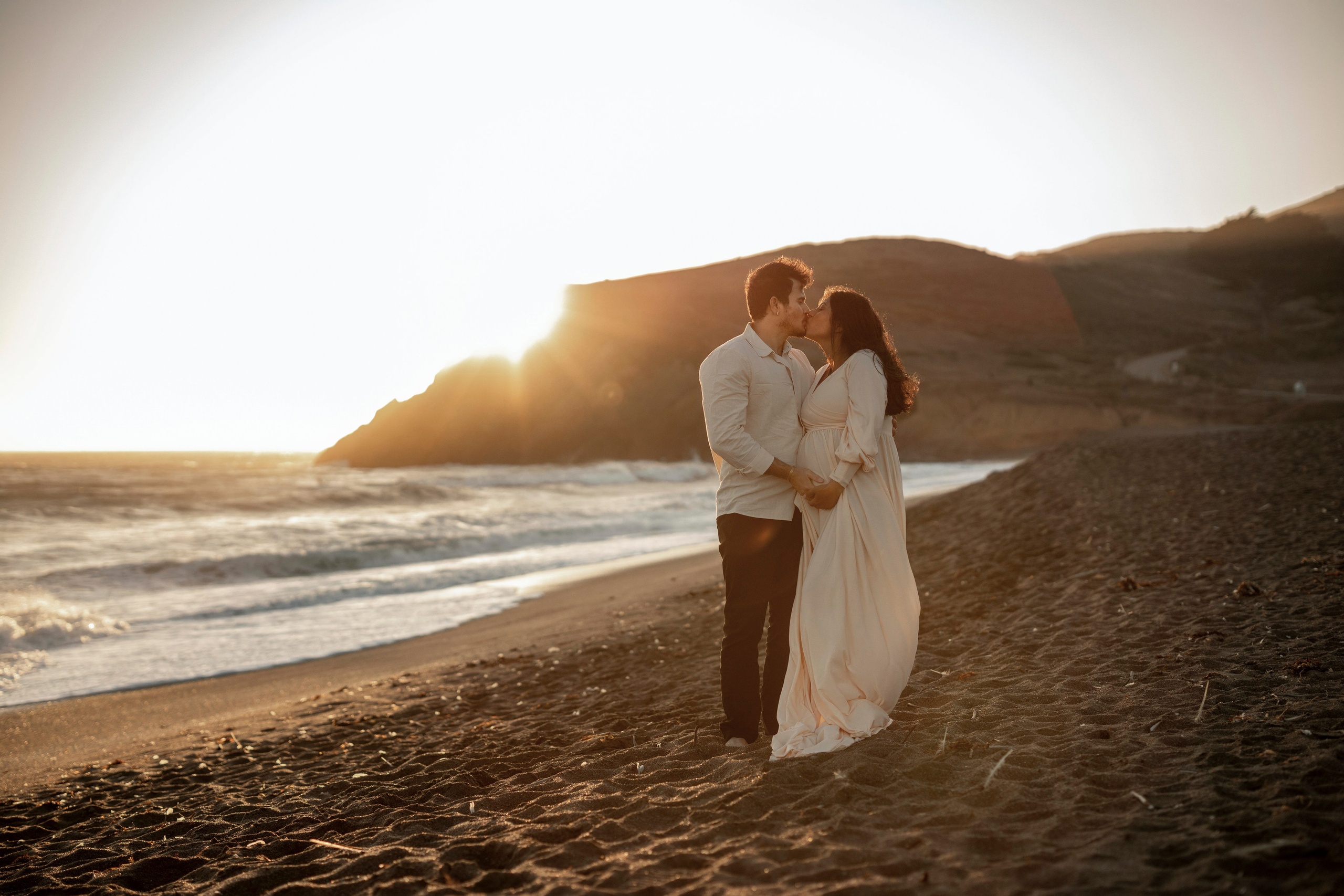 Romantic beach maternity photography of mom-to-be and dad holding baby bump