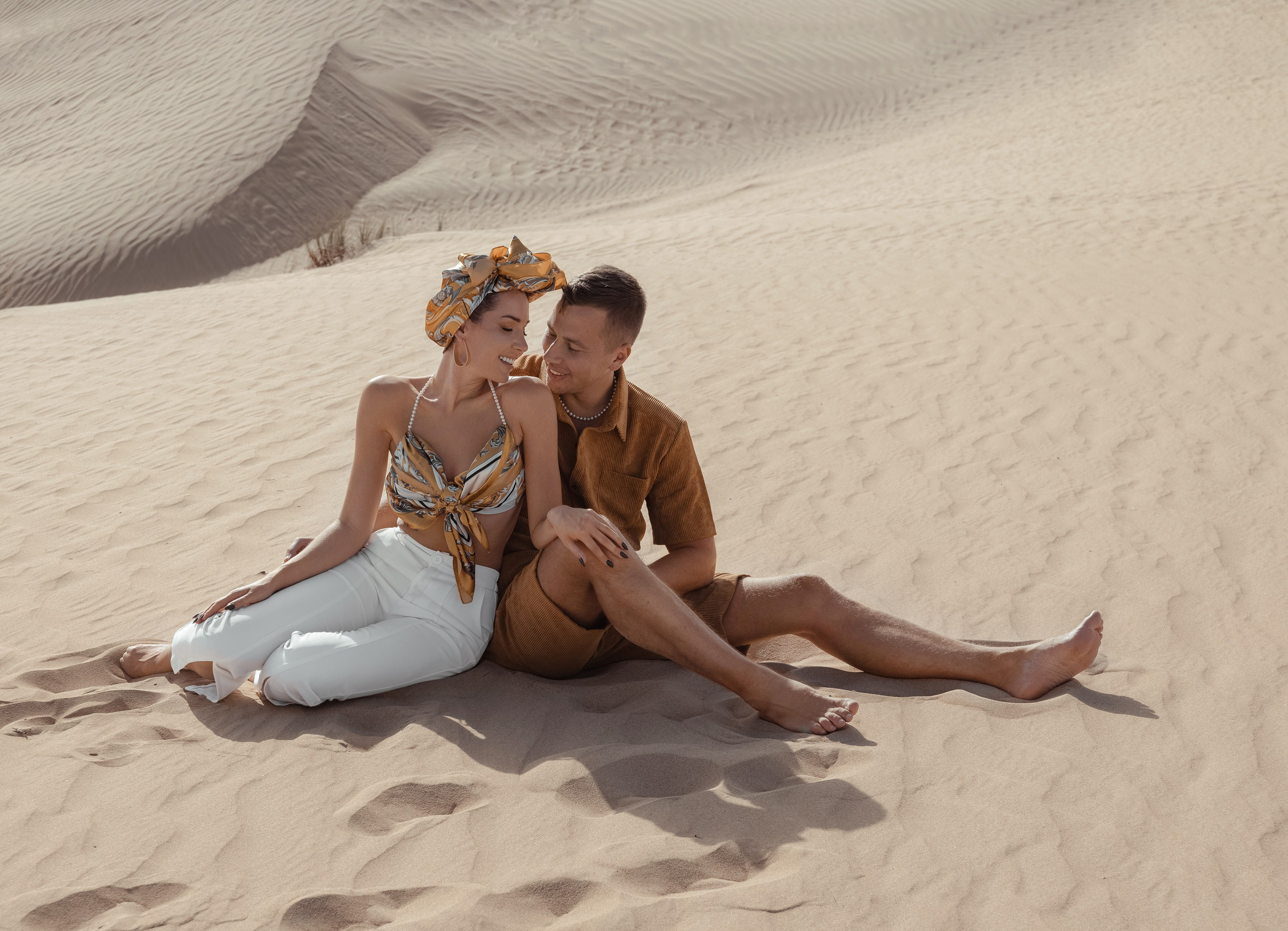 A couple connects in the desert, playfully interacting and holding each other, with the serene beauty of the landscape enhancing the moment. Dubai, United Arab Emirates
