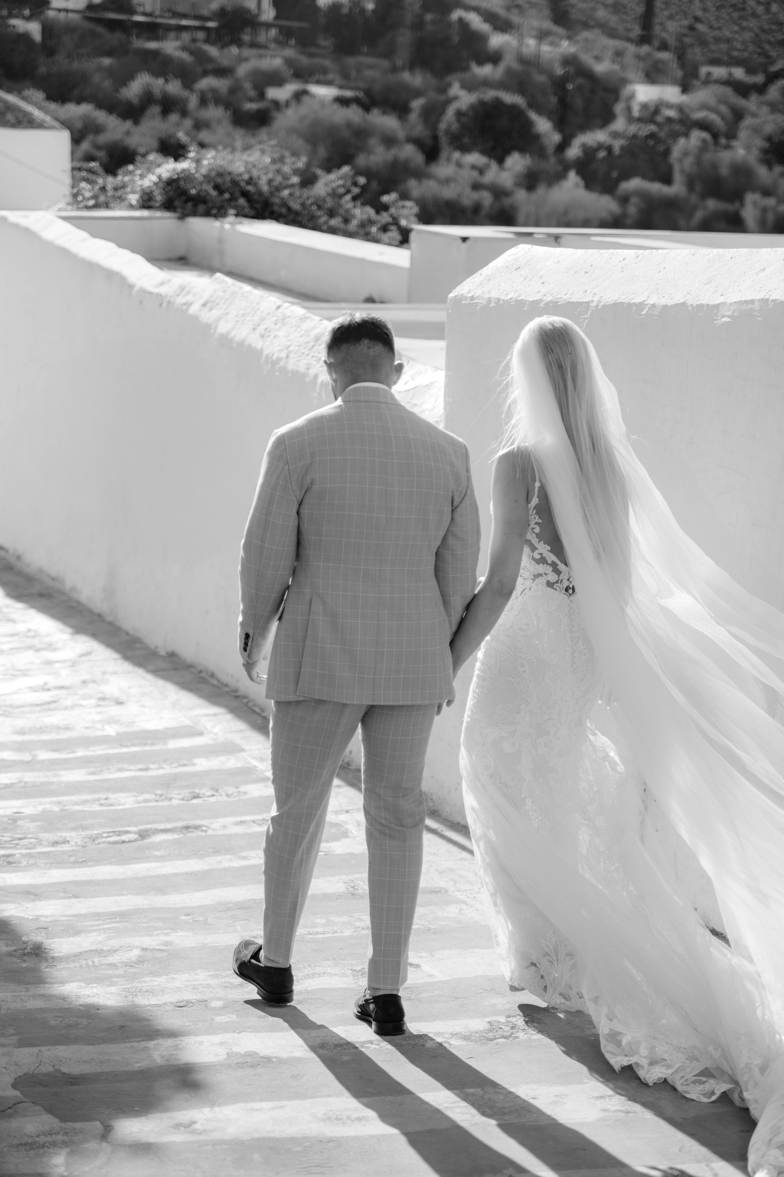 Bride and groom enjoying a quiet moment together on a cobblestone street in Lindos, with traditional Greek architecture around them