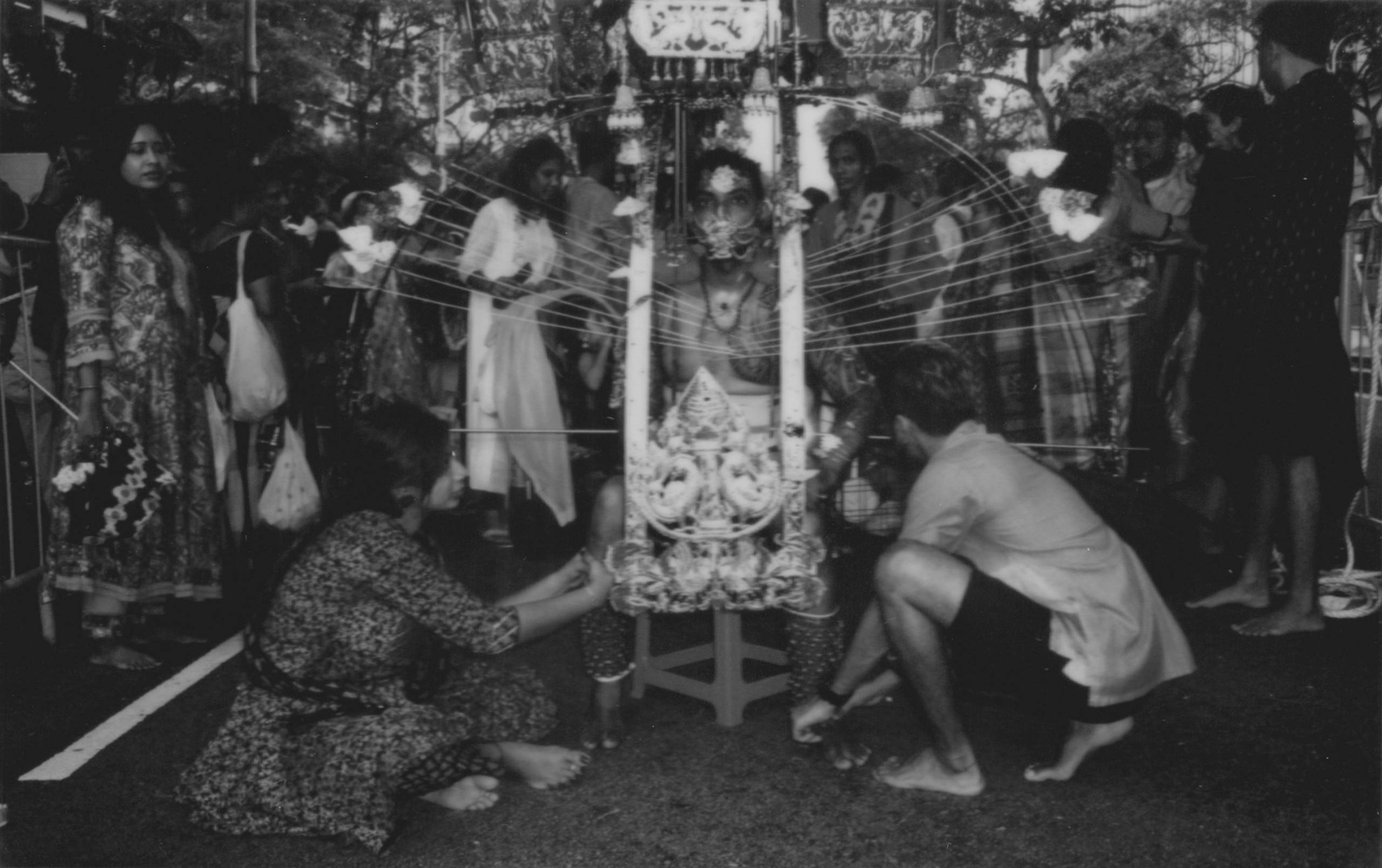 A dynamic black-and-white photograph documenting a Thaipusam devotee surrounded by family and supporters as they prepare him for a sacred ritual in Singapore. The intricate kavadi structure and emotional interactions highlight the depth of the cultural moment. This image showcases the photographer’s expertise in reportage and event photography, capturing authentic stories and meaningful connections—ideal for clients seeking immersive visual storytelling for cultural or corporate events.