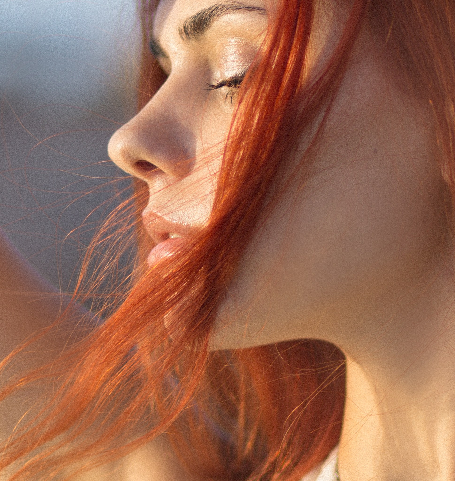 Крупный портрет женщины с ярко-рыжими волосами, с акцентом на ее профиль, освещенный солнечным светом, в Валенсии, Испания