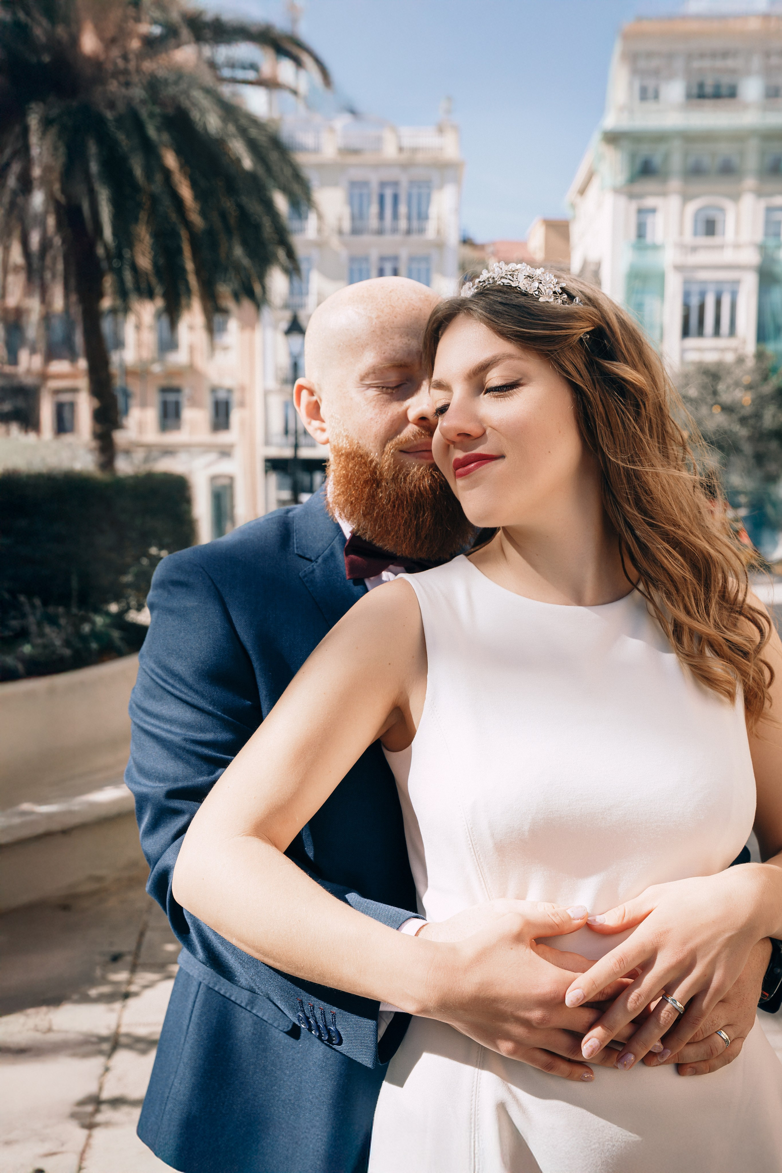 The bride smiles as the groom embraces her in the heart of València following their civil wedding ceremony. This elegant city wedding portrait showcases natural emotions and modern documentary wedding photography in Spain.
