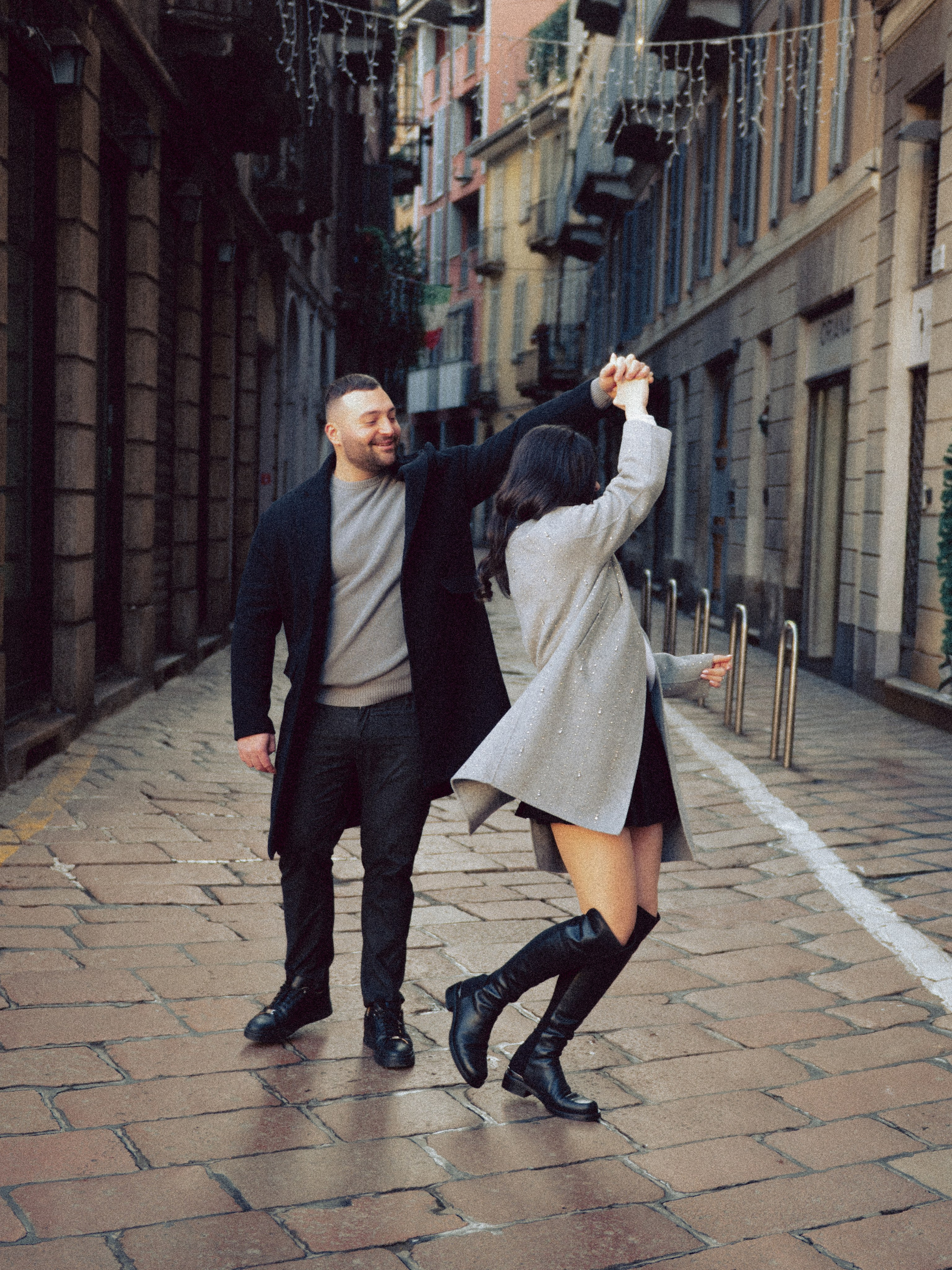 Coppia che balla e ride in una strada storica di Milano, momento spontaneo e romantico durante un servizio fotografico di coppia. servizio fotografico coppia Milano, coppia innamorata Italia, fotografia naturale di coppia, coppia in movimento Milano, servizio fotografico spontaneo Milano, amore e viaggio Italia, servizio fotografico di coppia Milano, fotografia love story Milano, coppia romantica Italia, ritratto di coppia Milano, primo piano coppia innamorata, fotografia emozionale Milano,