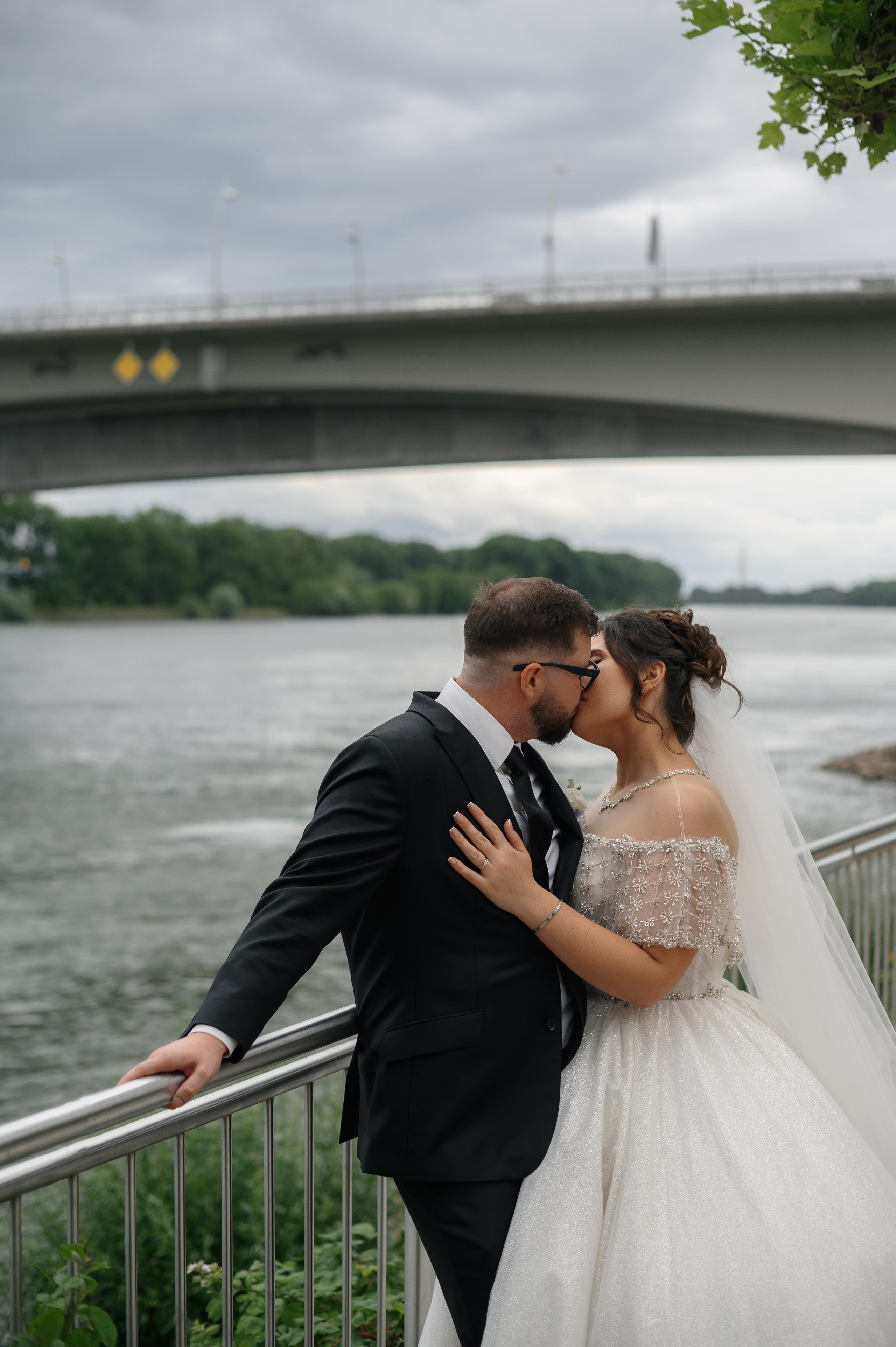 Kuss am Rheinufer mit einer Brücke im Hintergrund