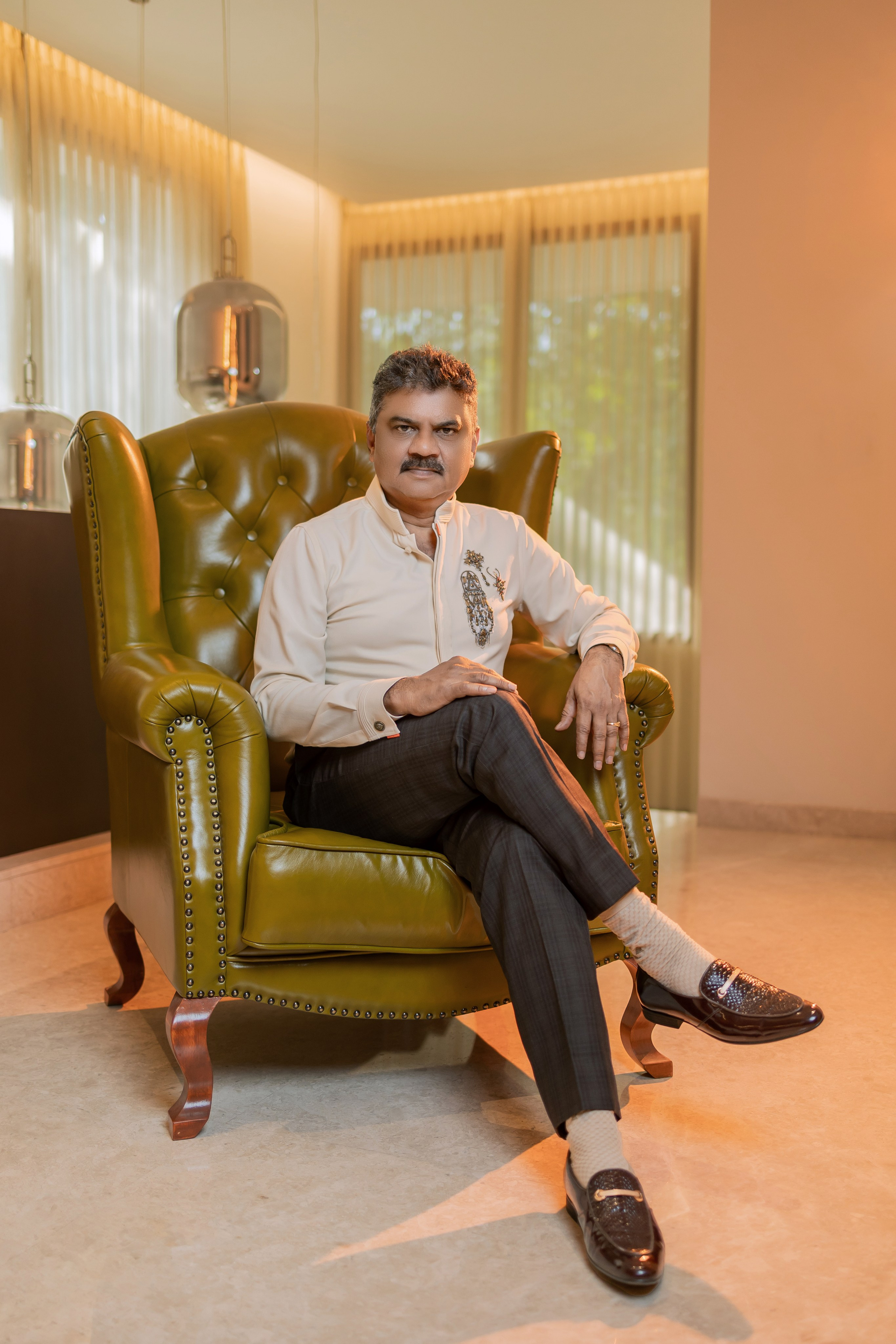 professional studio portrait of a man sitting in an olive green leather armchair in Malleshwaram, Bengaluru