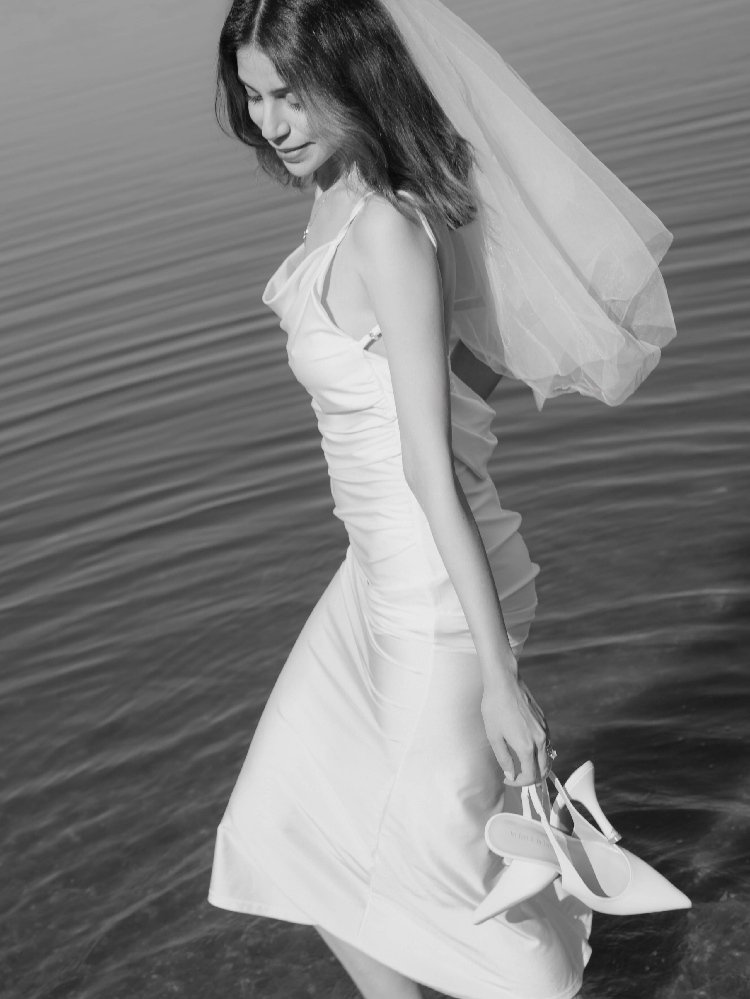 Bride holding her shoes feet in the water, Tbilisi Lisi Lake.