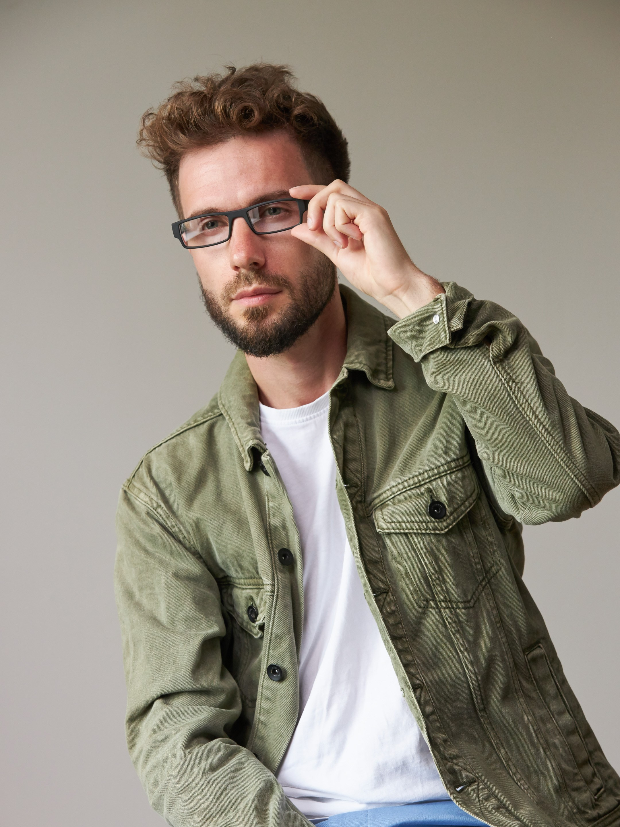 Eyewear model photoshoot - studio portrait of a young man on warm grey background - photographer Andrey Dunin