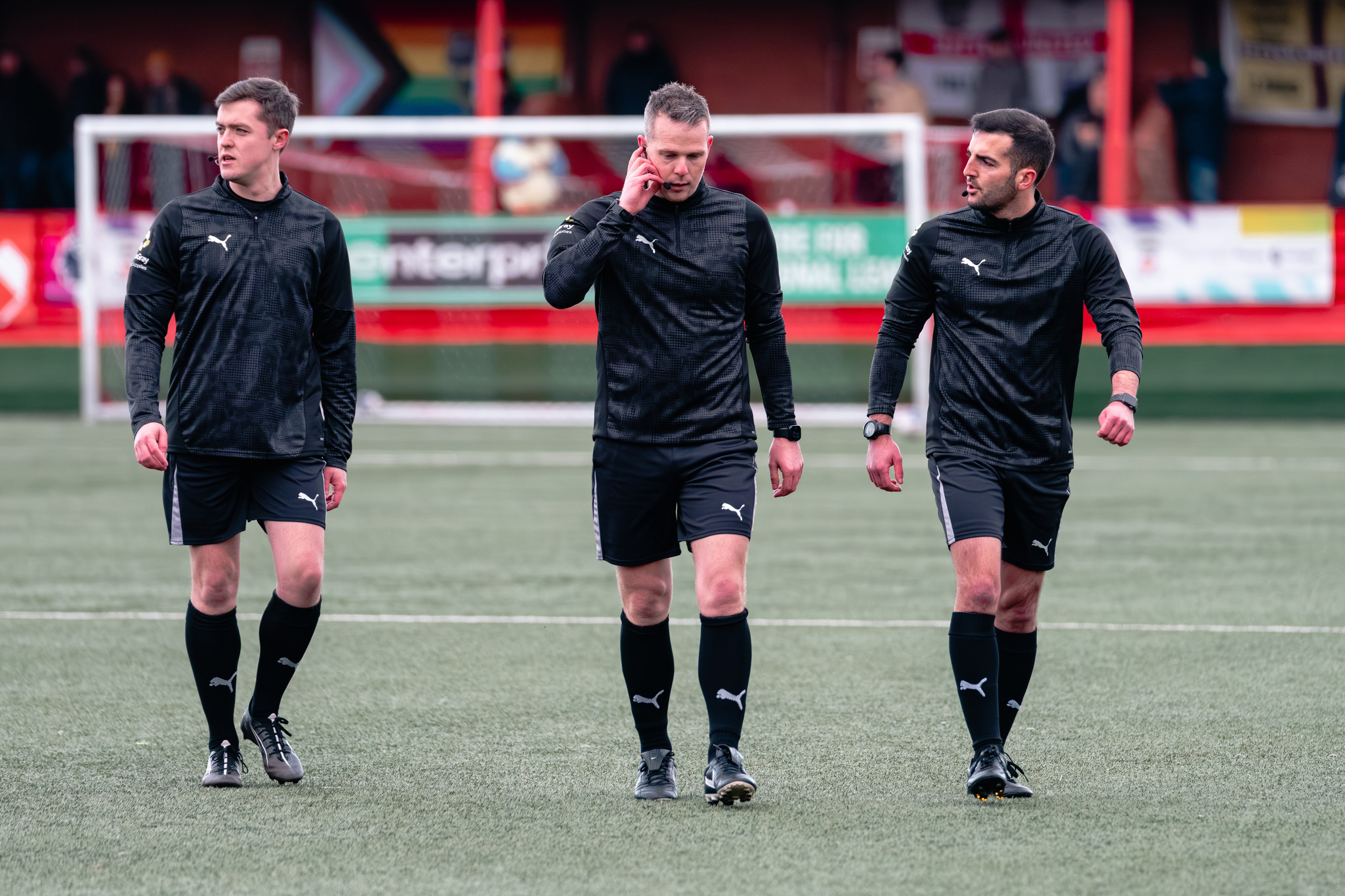 Referee George Laflin and assistants James Hooper and Ciaran Barlow walk across the pitch before the match